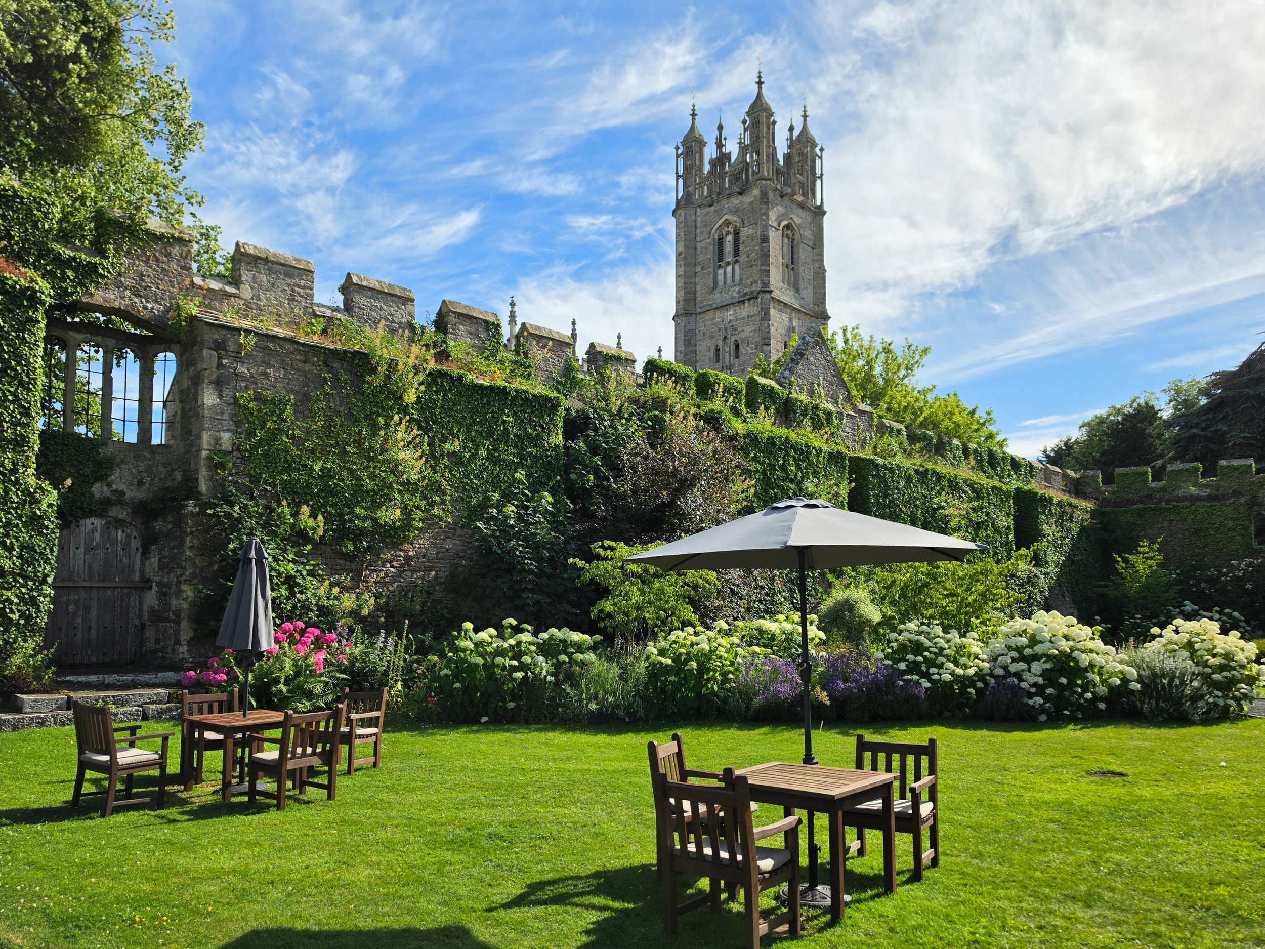 Peaceful castle gardens with manicured lawns, blooming flowers, and views of the historic church