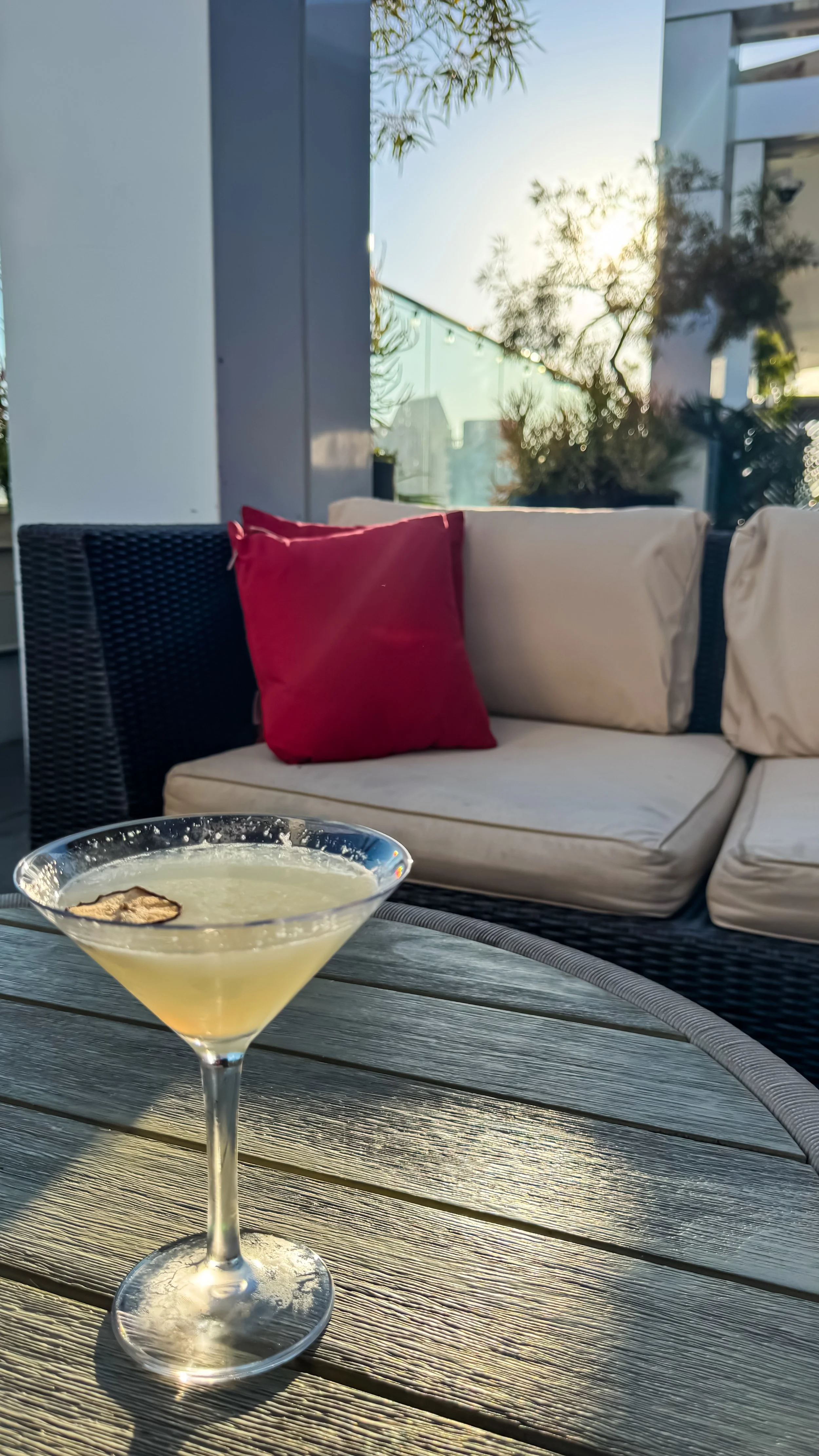 Signature cocktail served on the rooftop terrace during golden hour with comfortable outdoor lounge seating