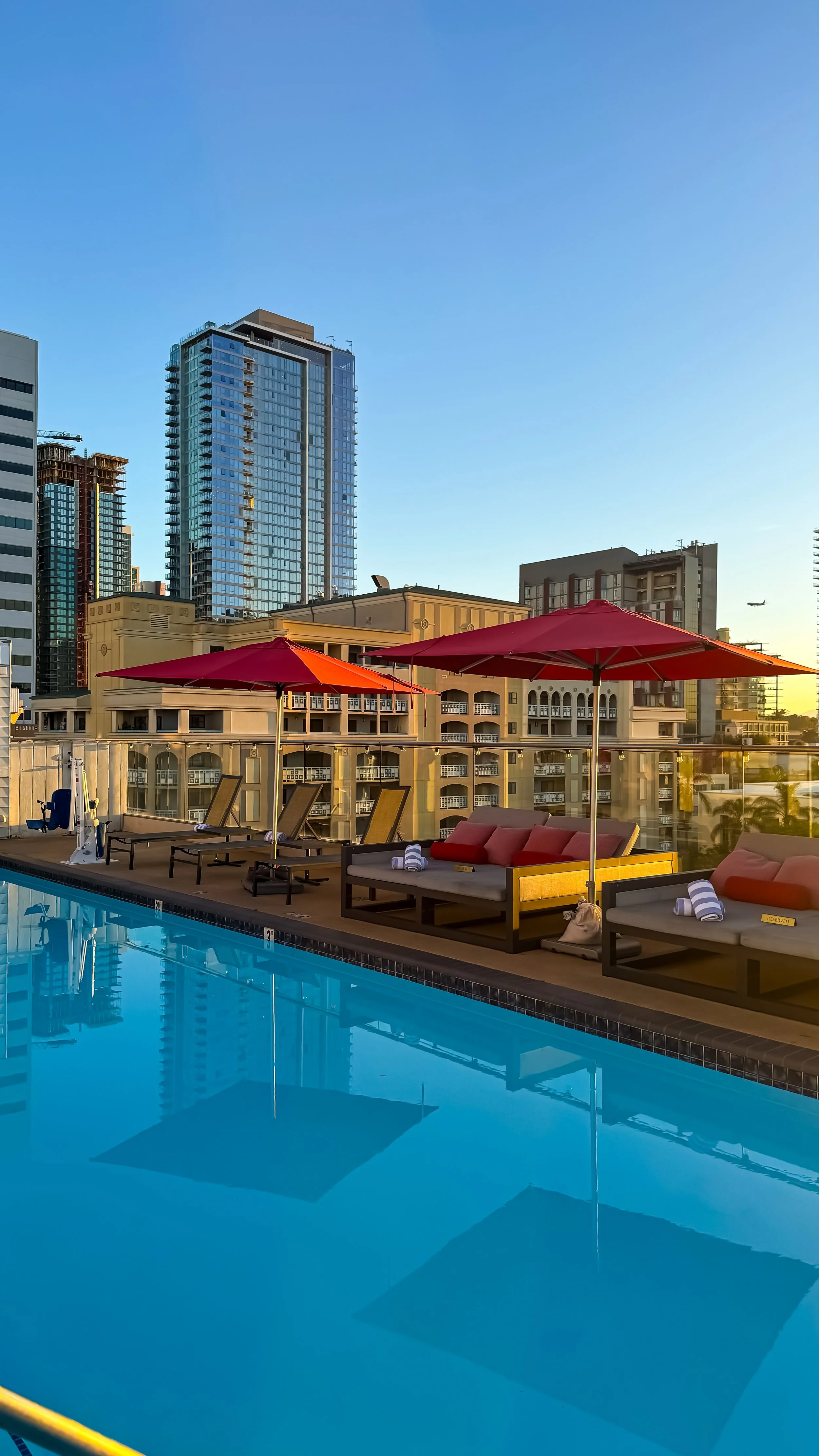 Rooftop swimming pool with red umbrellas, luxury loungers, and panoramic views of downtown San Diego