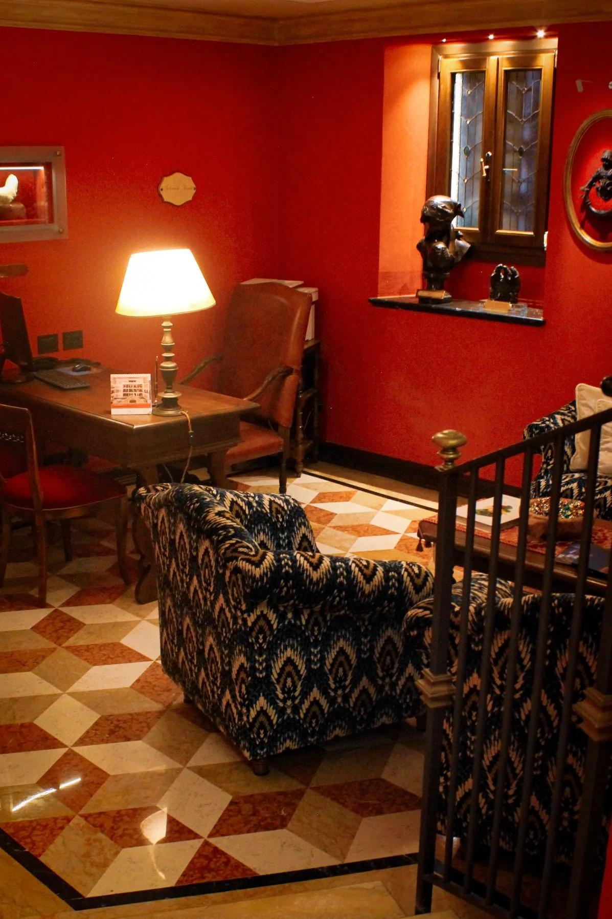 Elegant reception lounge with rich red interiors, marble flooring, and classic Italian furnishings