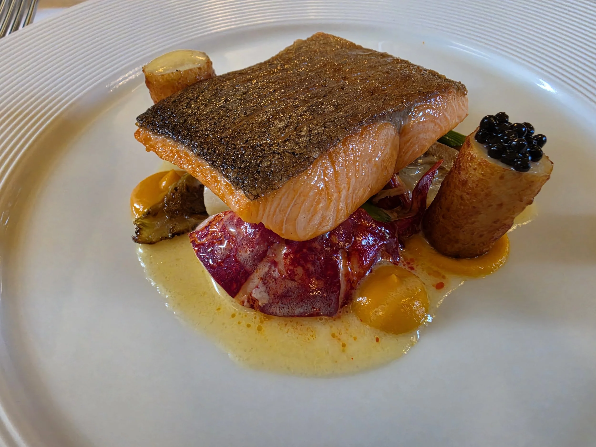 Pan-seared salmon served with seasonal vegetables and beautifully presented gourmet accompaniments