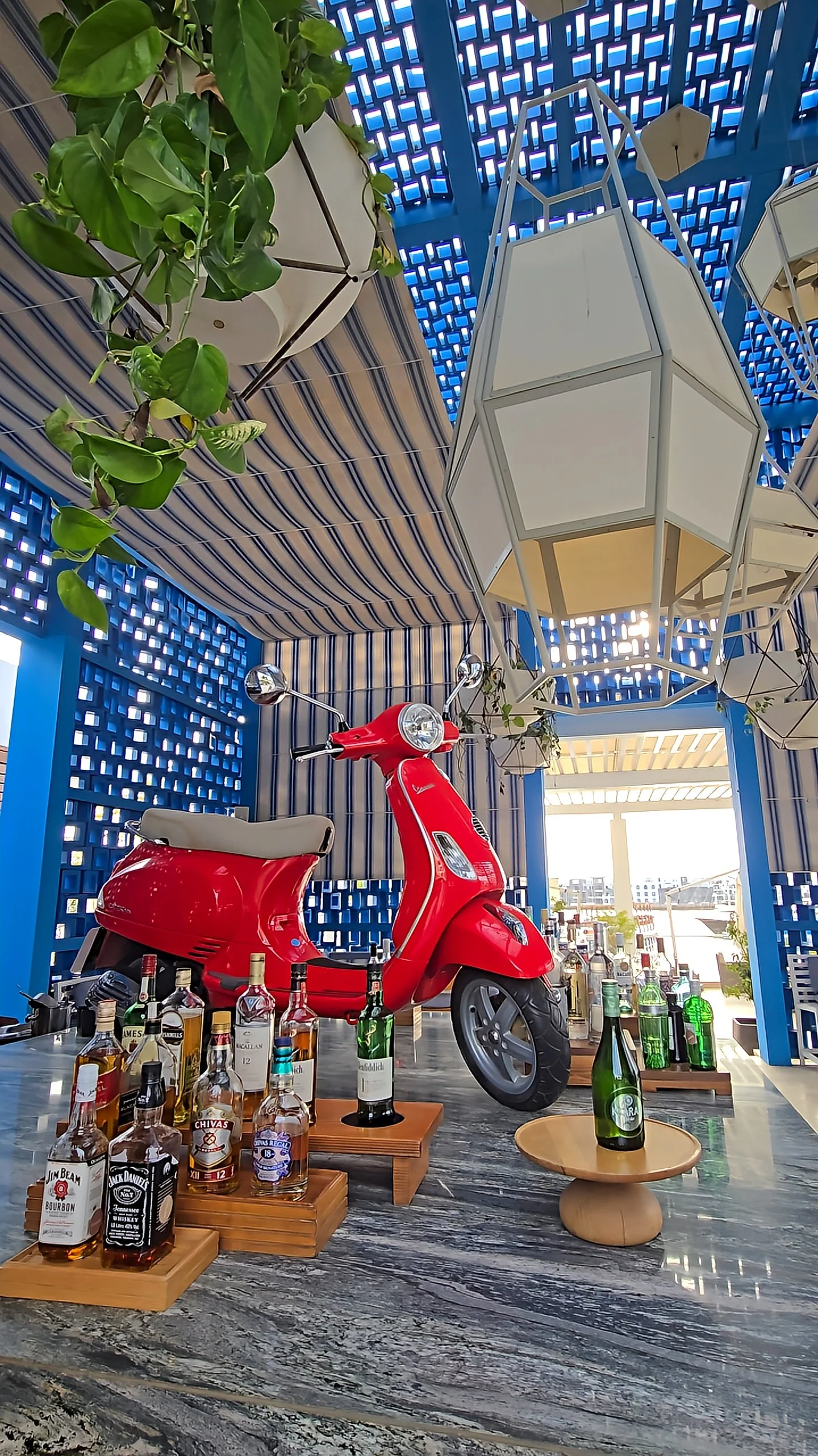 Vibrant indoor bar with red Vespa display, geometric blue walls, and curated spirits selection, Hyatt Regency Aqaba Ayla Resort – Aqaba, Jordan.