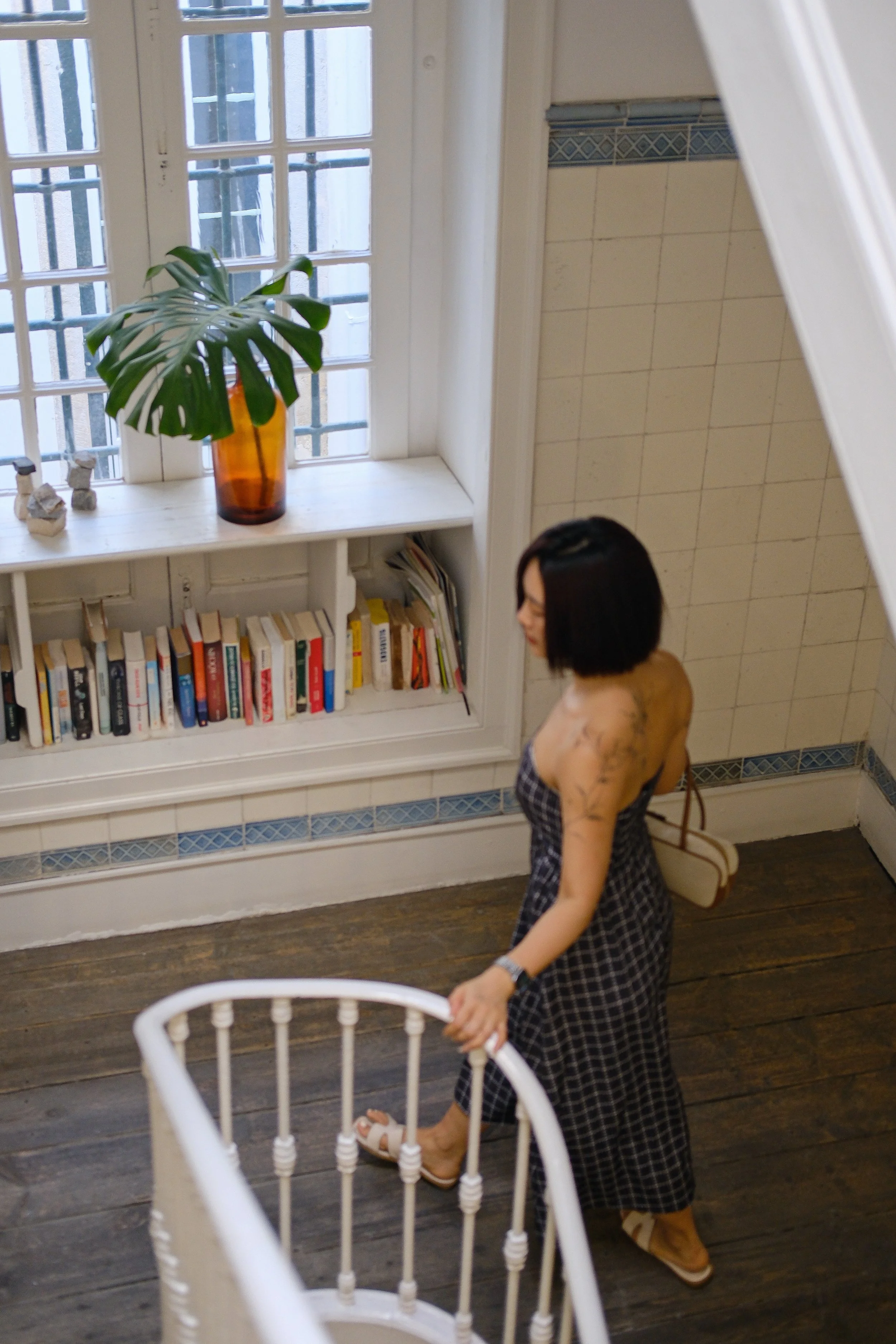Bright apartment staircase with books, natural light, and Portuguese design touches