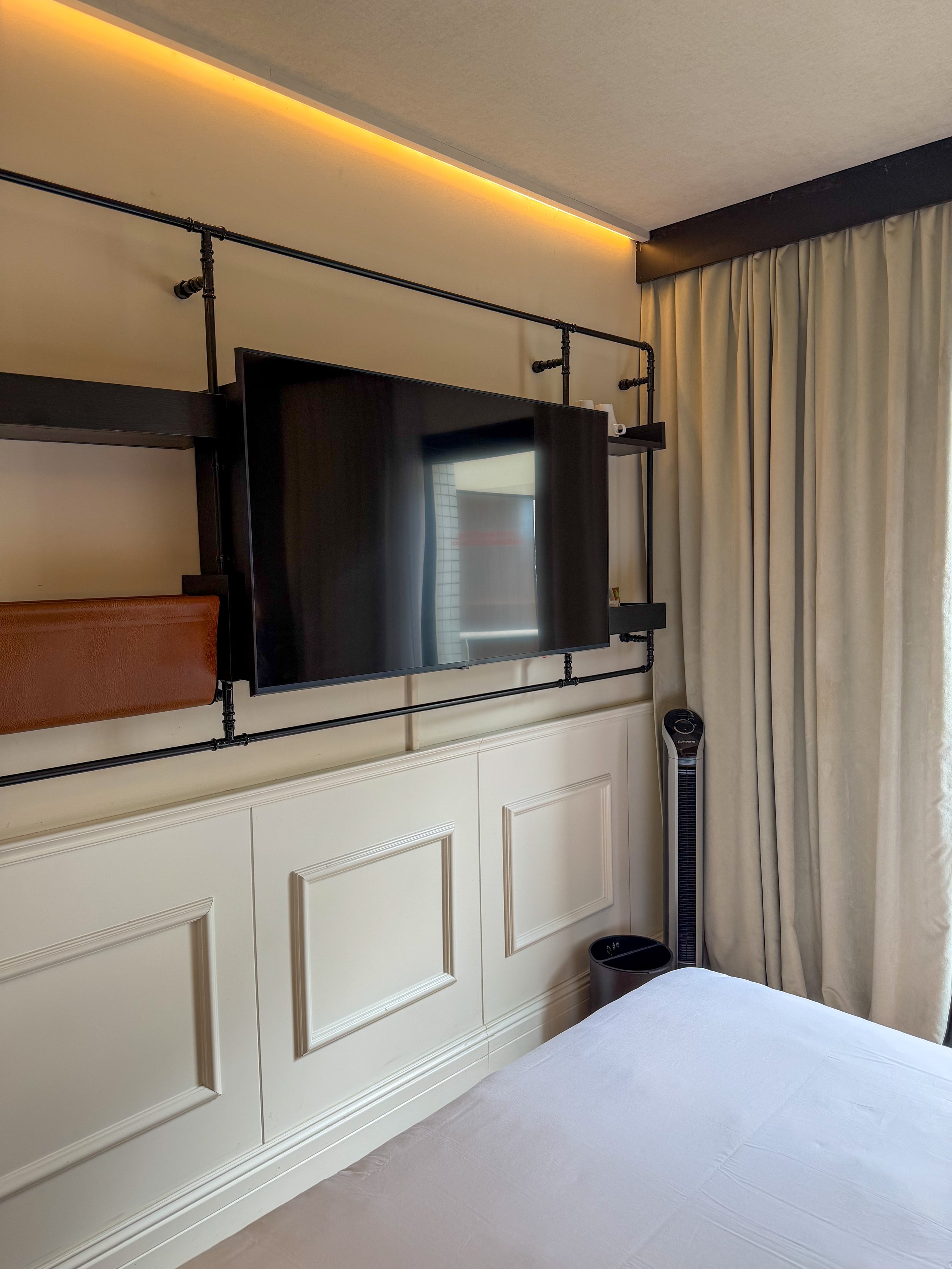 Contemporary guest room featuring industrial shelving, smart television, and clean design