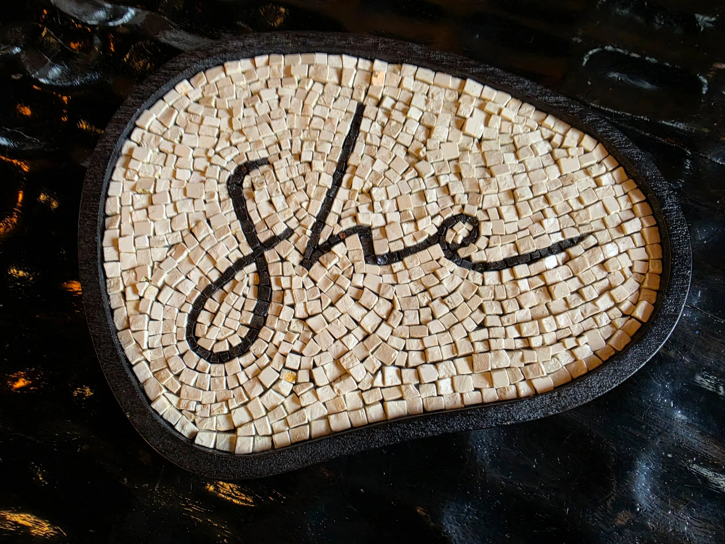 Artistic mosaic detail featuring the She logo inside She Mykonos Hotel in Mykonos, Greece