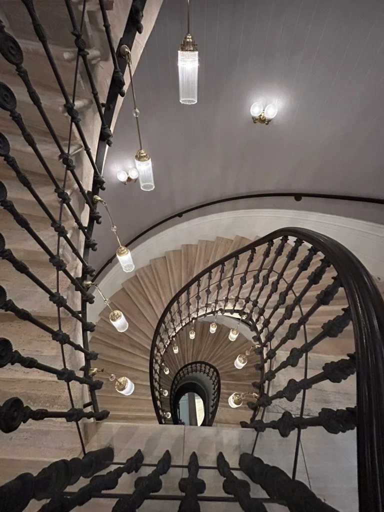 Iconic spiral staircase with ornate iron railings and hanging lights