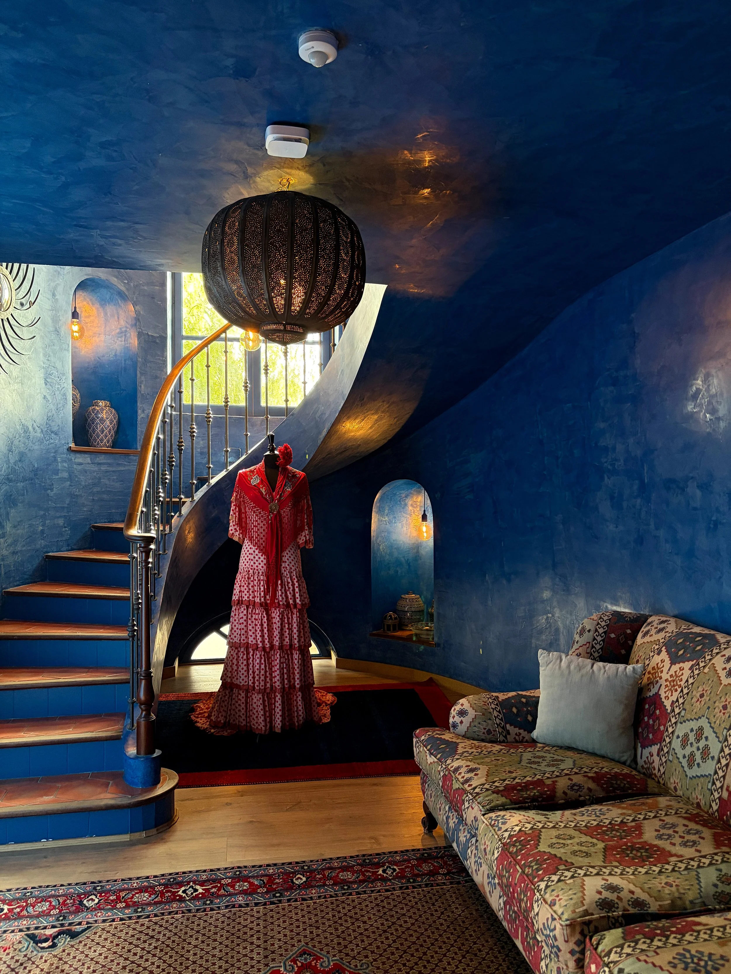 Curved blue staircase with handcrafted details and vibrant Spanish-inspired décor