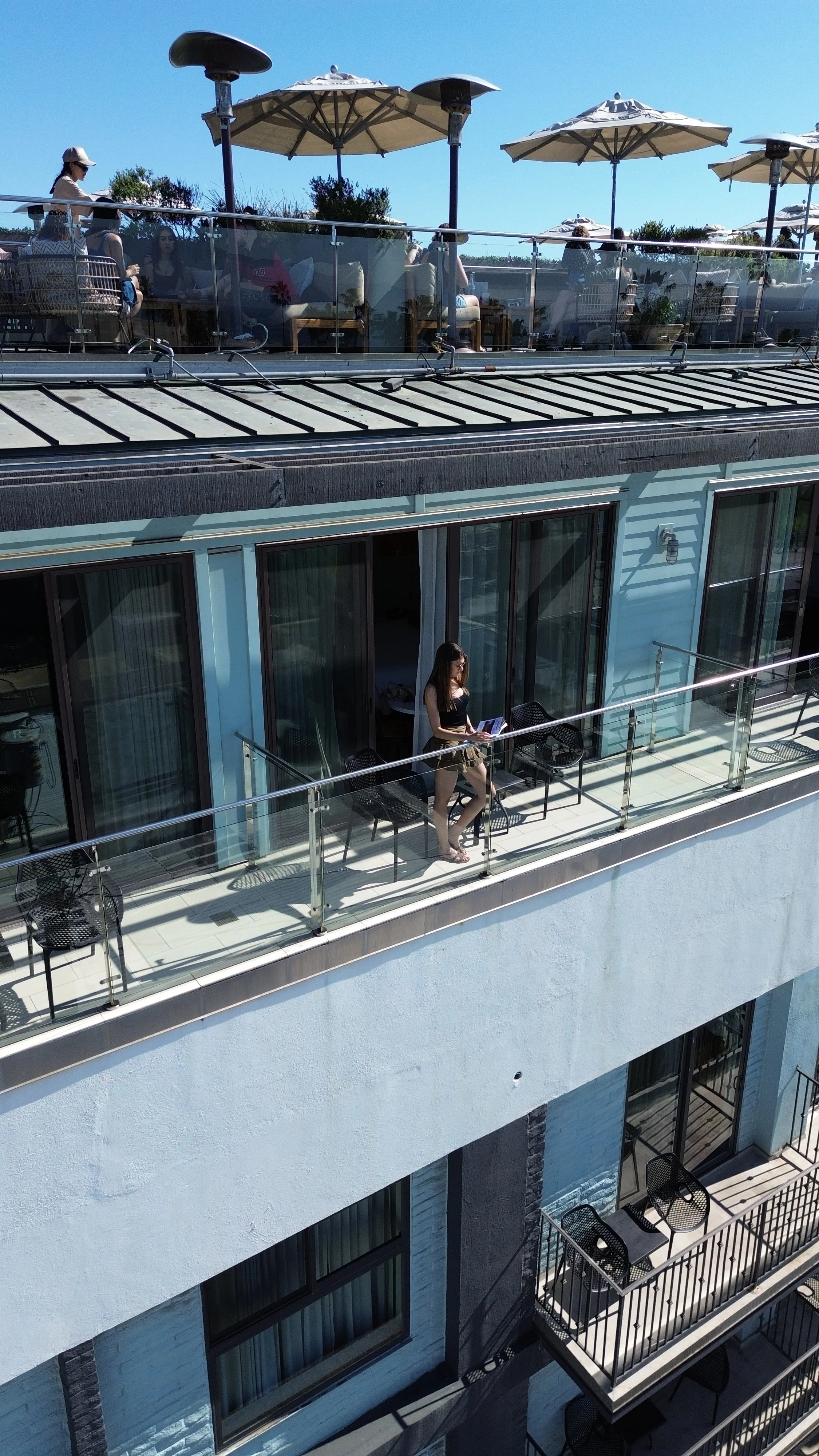 Private balcony beneath the rooftop lounge offering stylish outdoor seating and coastal city views