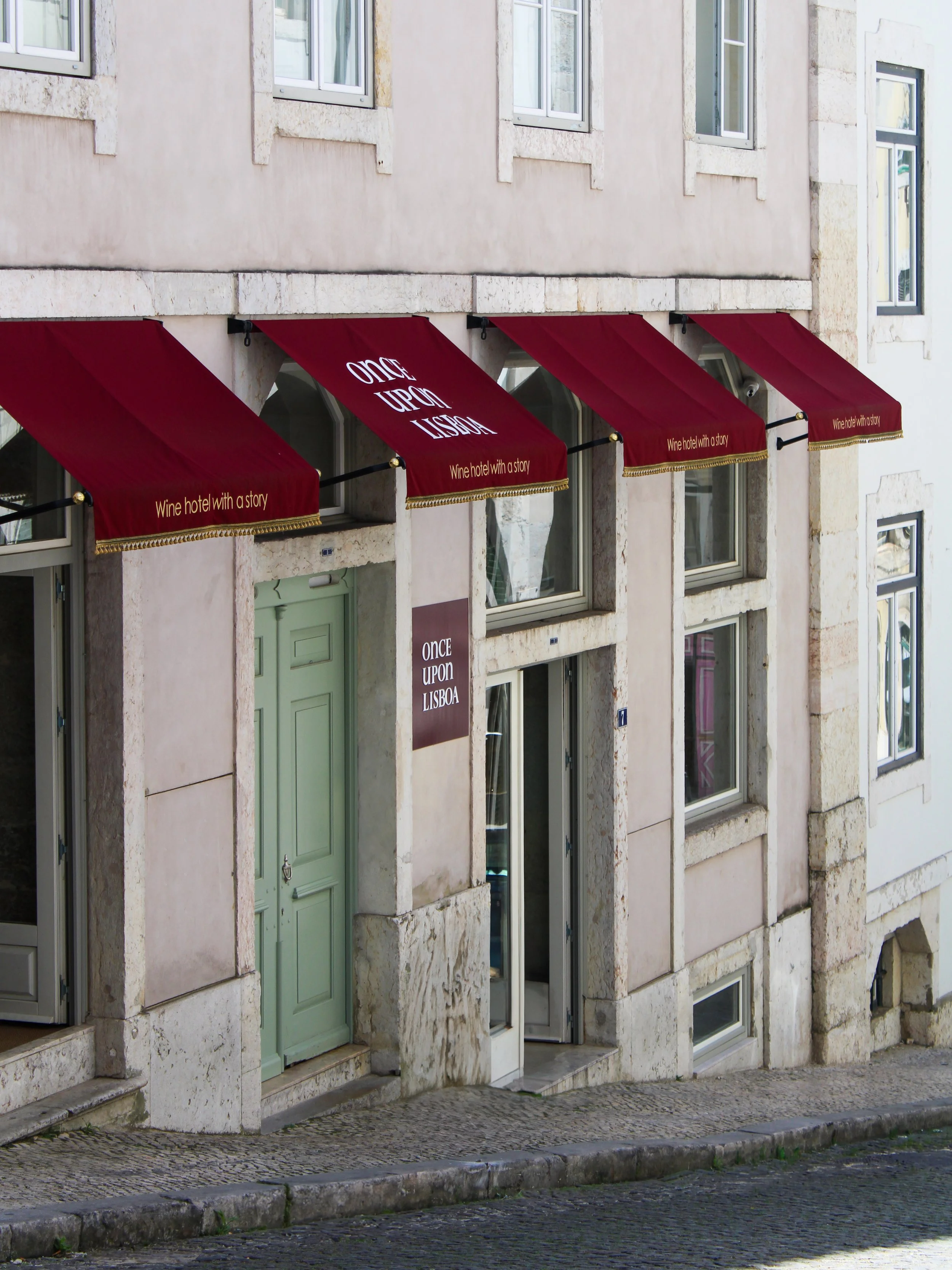 Exterior façade of Once Upon Lisboa featuring its signature burgundy awnings in Lisbon, Portugal