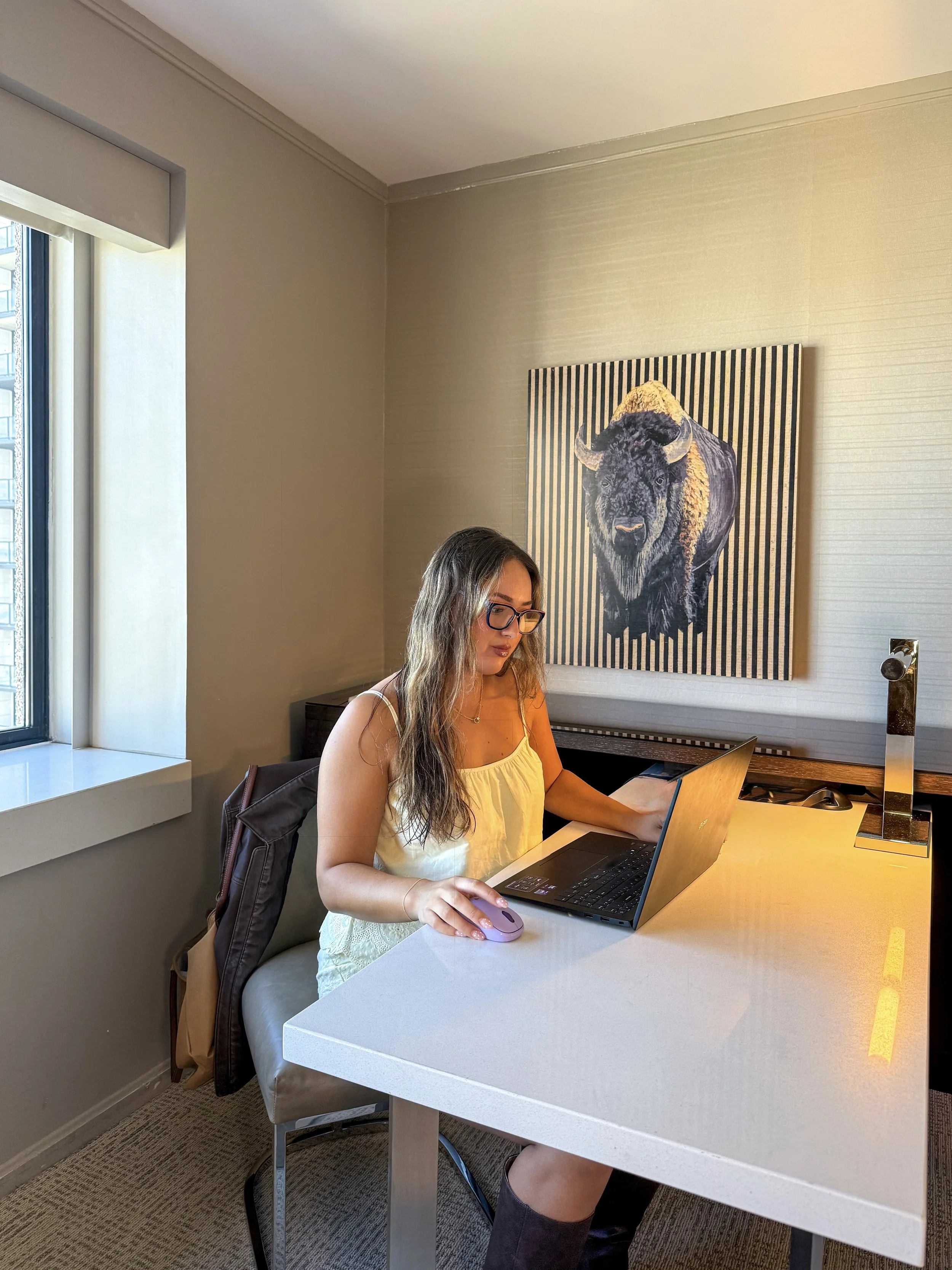 Guest working at a spacious desk beside a window in a modern hotel room