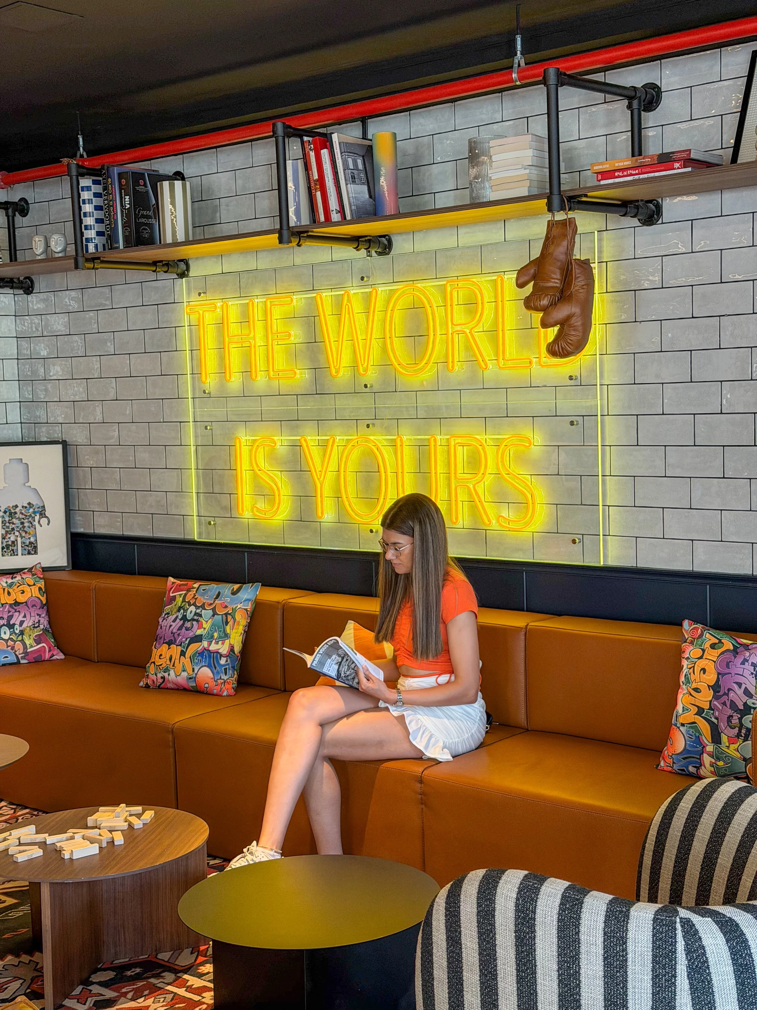 Guest relaxing beneath the iconic ‘The World Is Yours’ neon sign in the lounge