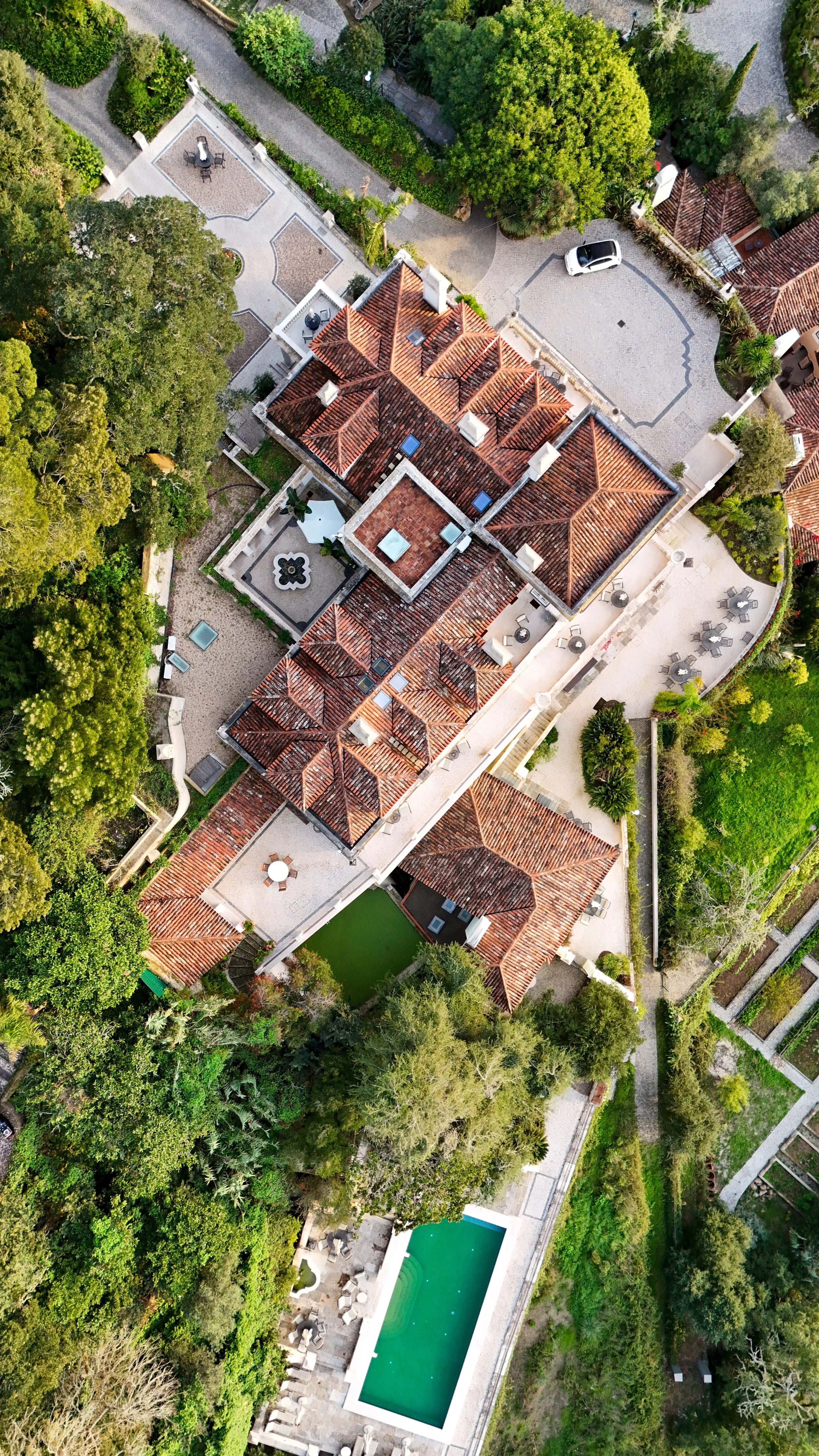 Aerial view of terracotta rooftops, garden paths, and the pool terrace woven into the hillside