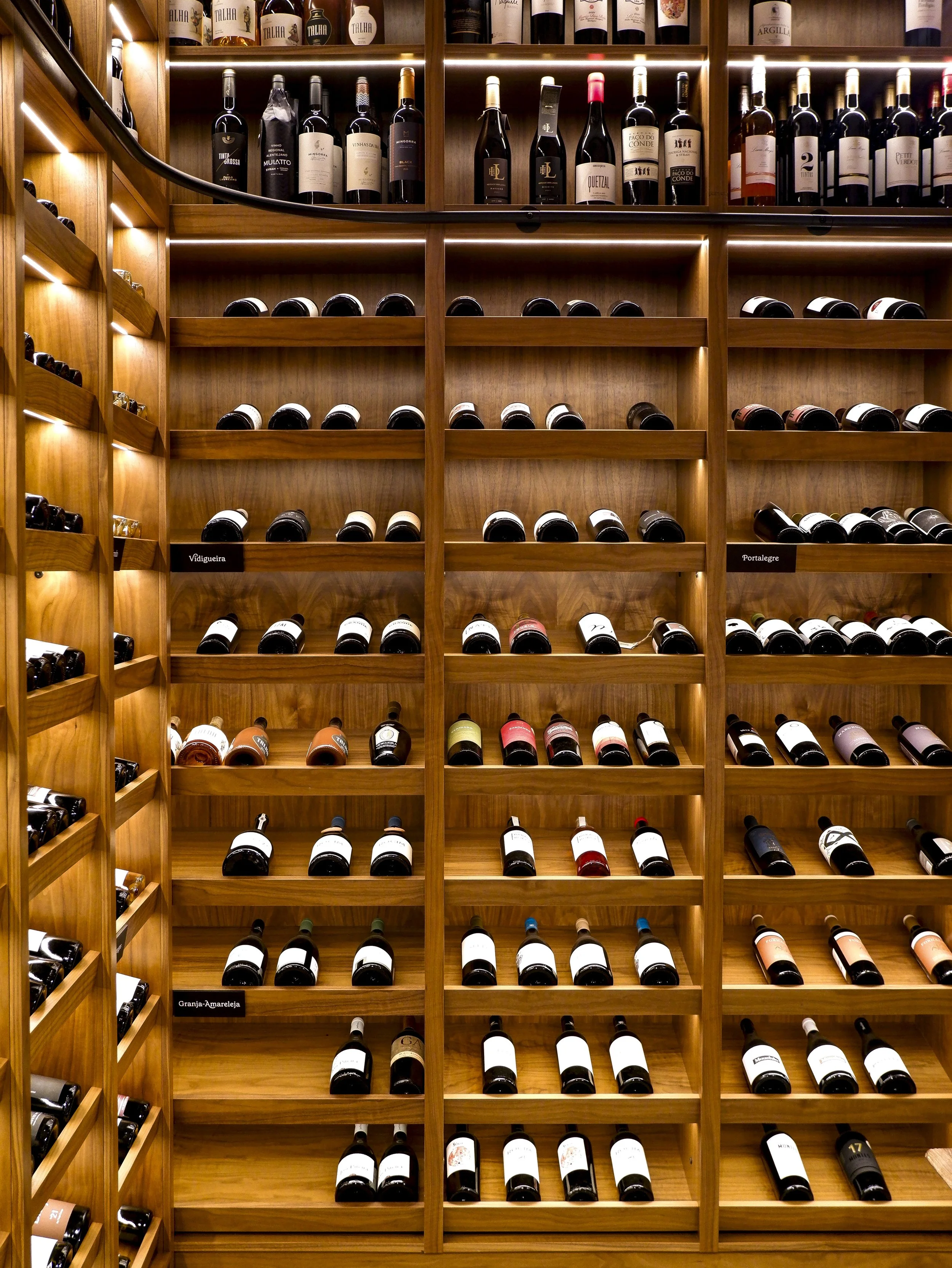 Climate-controlled wine cellar showcasing a curated selection of Portuguese wines displayed in warm wooden shelving — Octant Évora