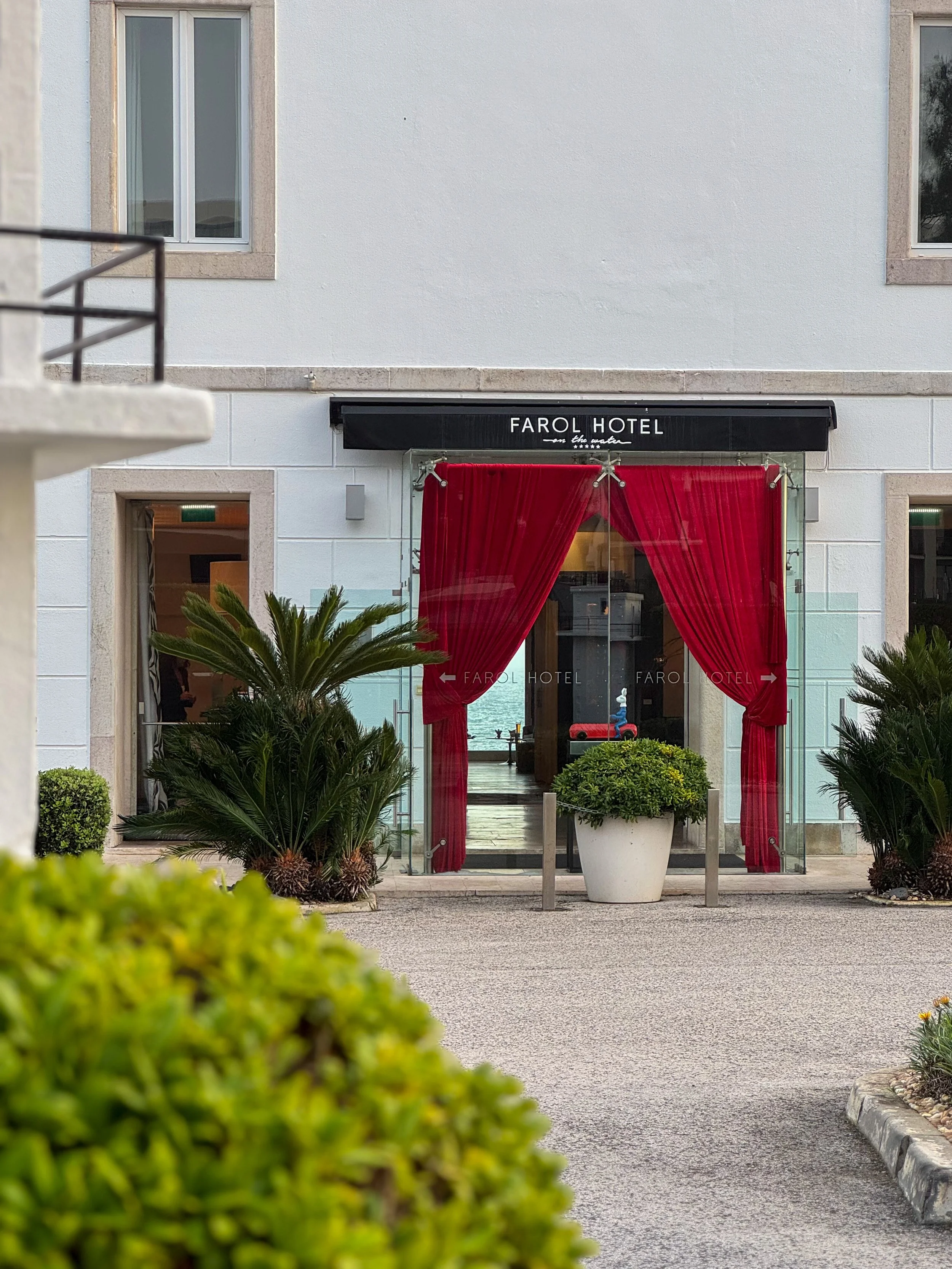 Grand entrance framed by iconic red curtains welcoming guests into Farol Hotel