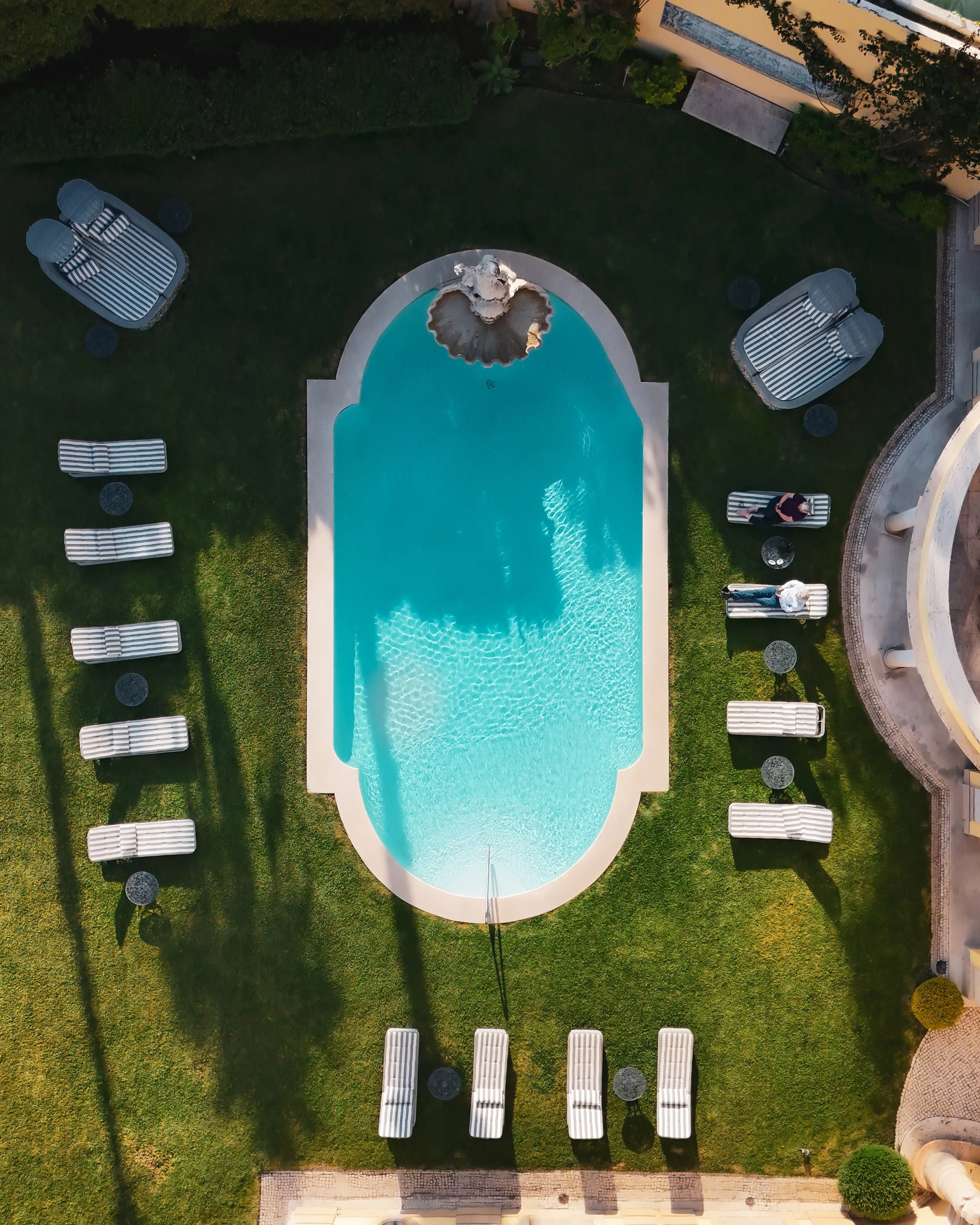 Aerial view of the pool framed by manicured gardens and sun loungers, capturing symmetry and serenity from above, Estoril Vintage Hotel – Estoril, Portugal.