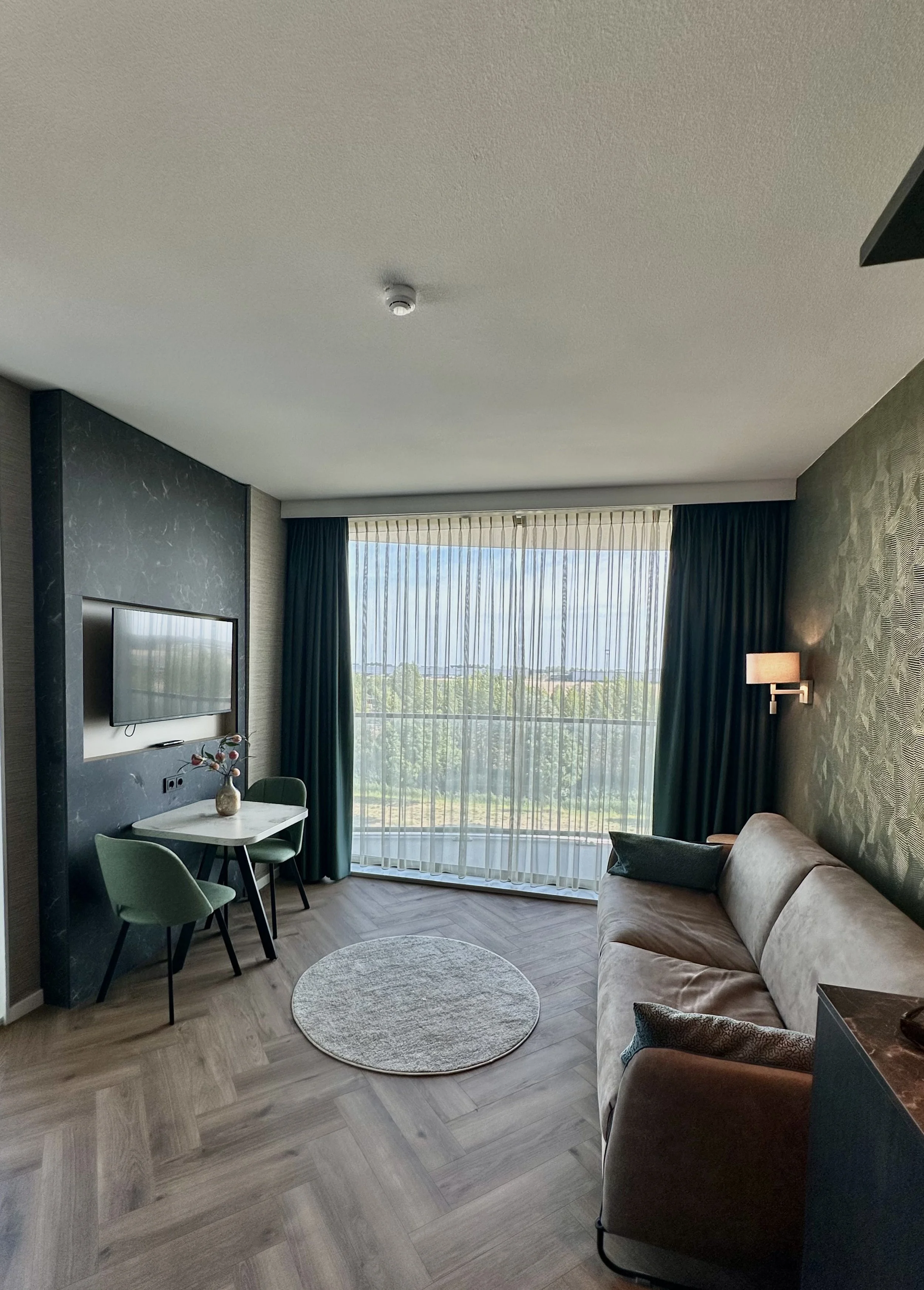 Spacious suite with modern furnishings and large windows overlooking greenery