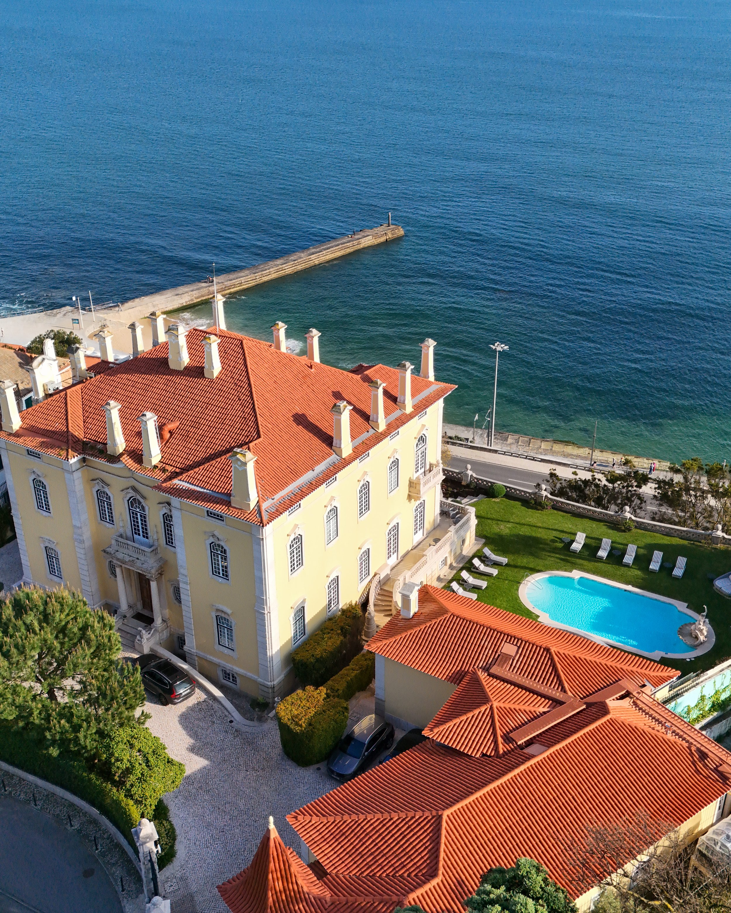 Coastal estate with terracotta roofs overlooking the Atlantic and private pool terrace in golden light, Estoril Vintage Hotel – Estoril, Portugal.