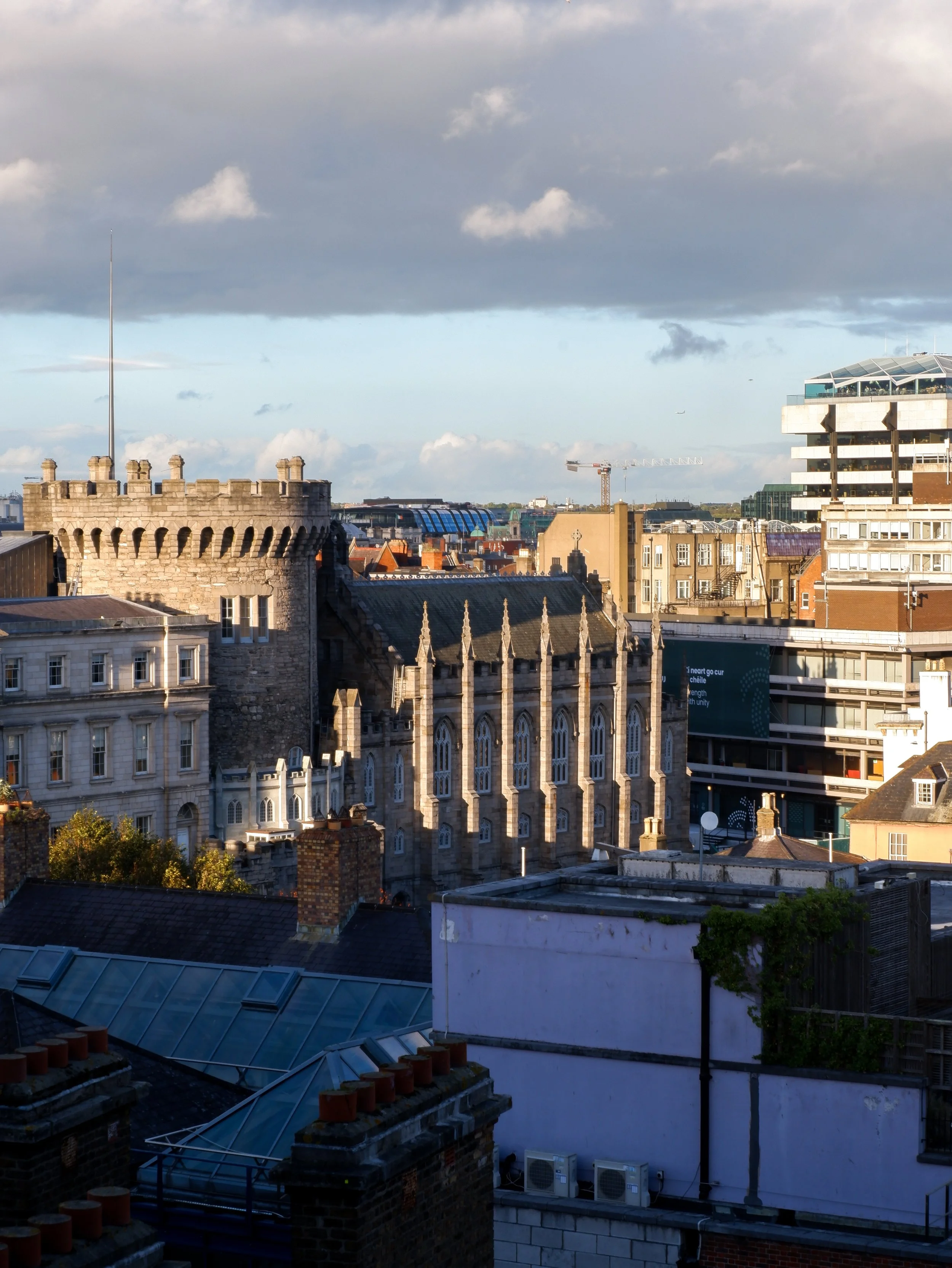 Elevated view of Dublin Castle and the surrounding city rooftops beneath a partly cloudy sky