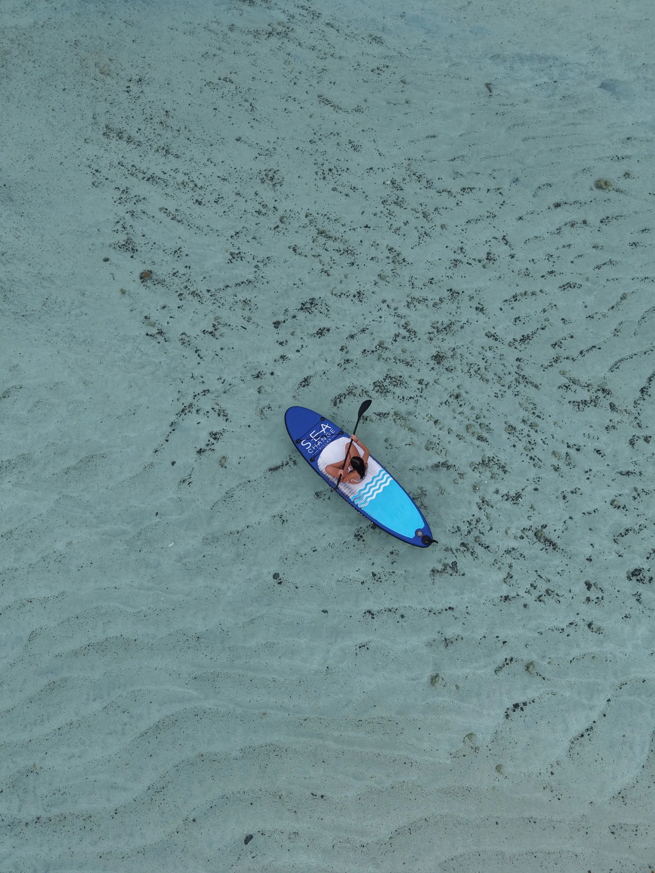 Paddleboarding over crystal-clear lagoon waters at Sea Change Villas in Rarotonga, Cook Islands