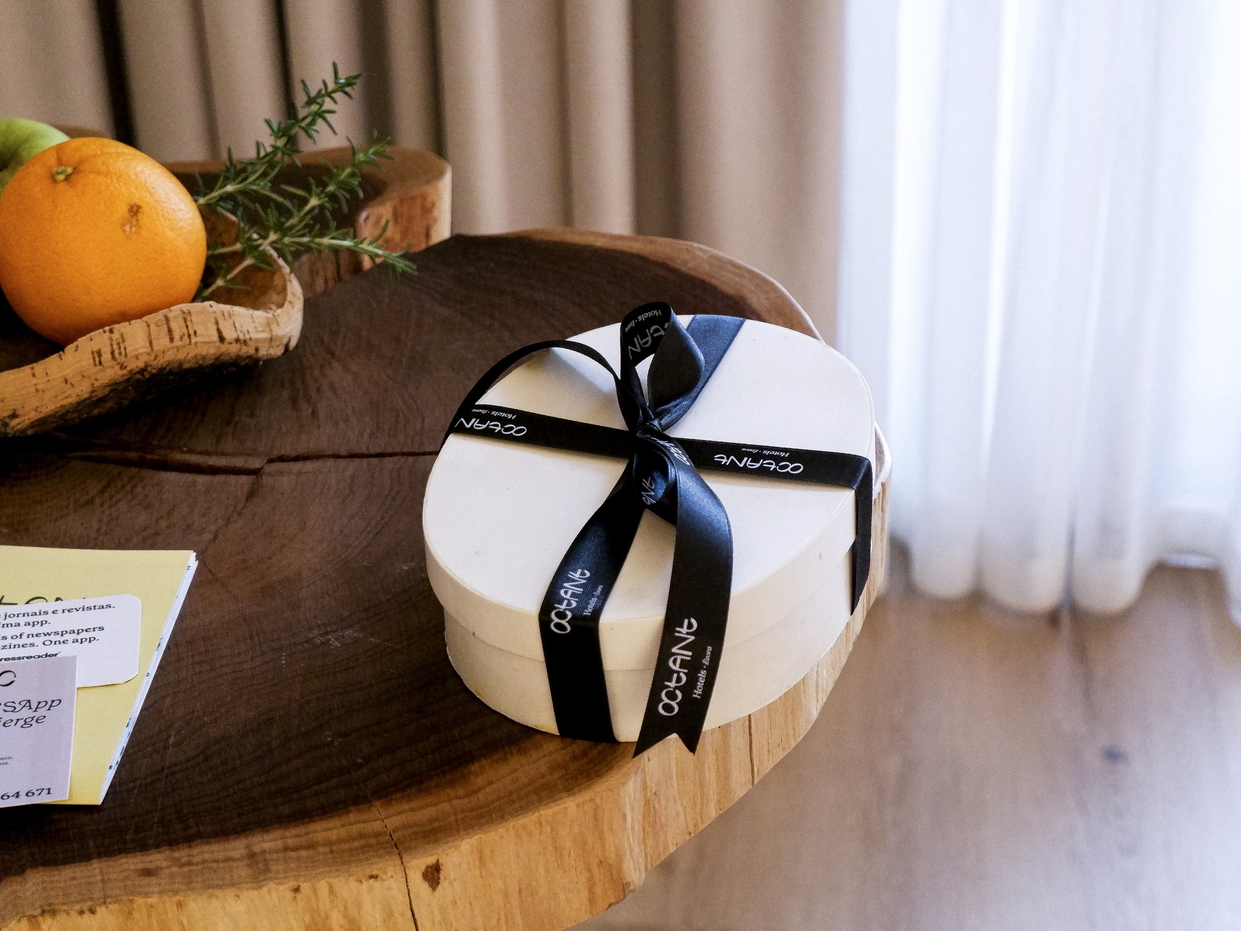 Thoughtfully prepared welcome gift with local fruit and branded packaging placed on natural wood surfaces — Octant Évora