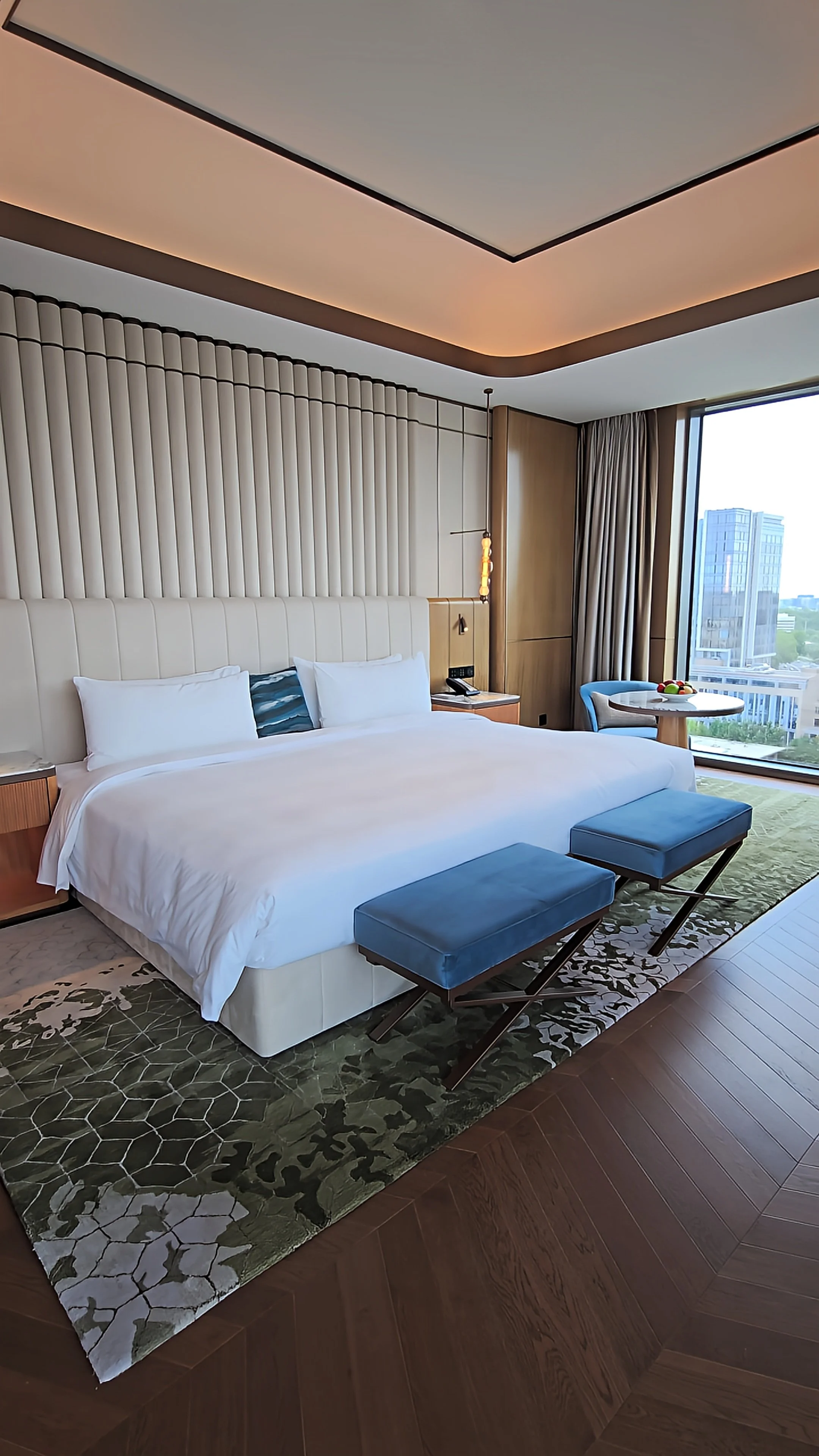 Spacious luxury guest room featuring floor-to-ceiling windows, modern furnishings, and panoramic city views