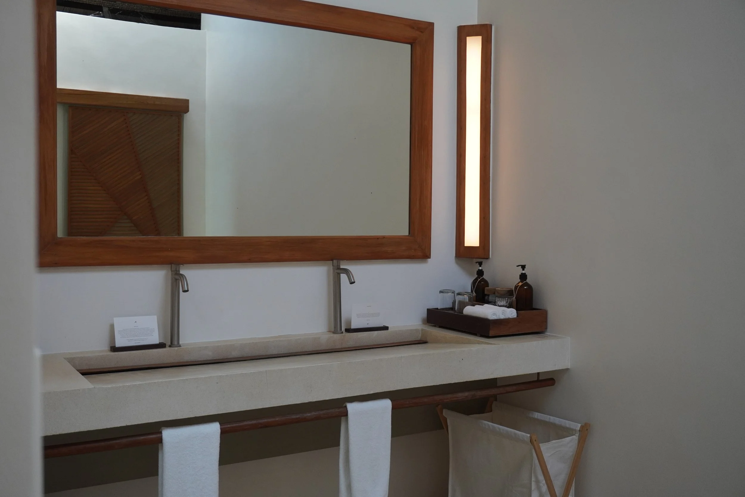 Minimalist bathroom with a double vanity, natural finishes, and premium amenities