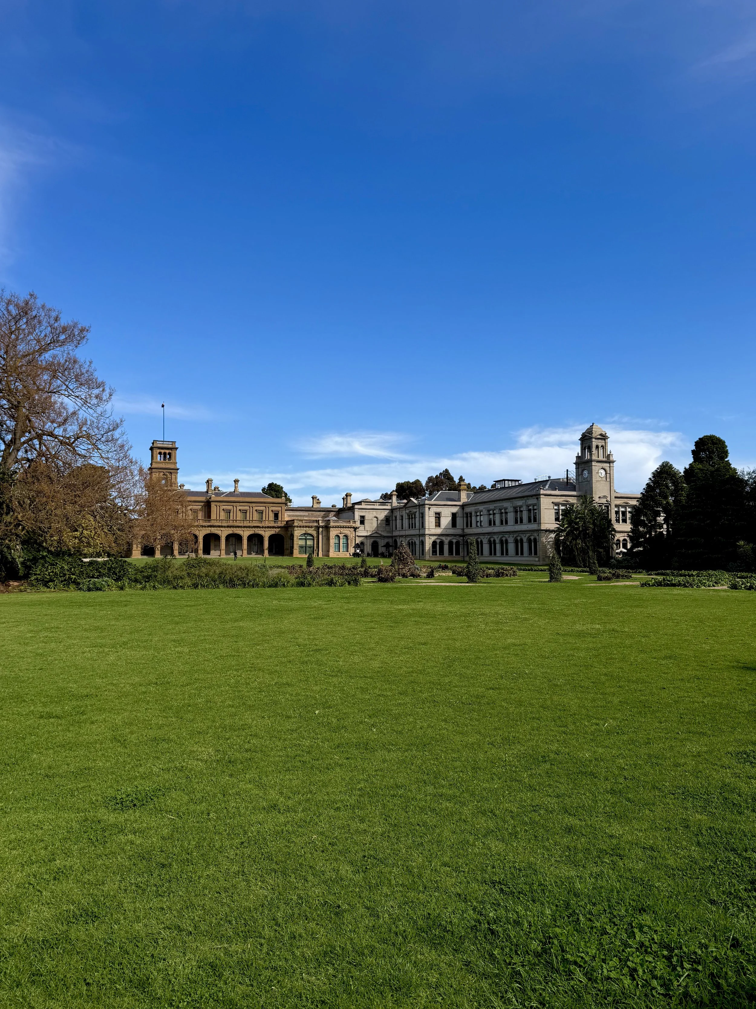 Grand heritage mansion surrounded by expansive green lawns, landscaped gardens, and mature trees