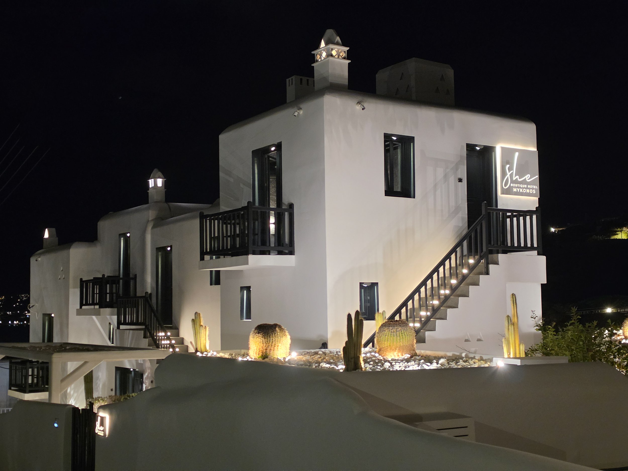 Whitewashed boutique hotel exterior illuminated at night at She Mykonos Hotel in Mykonos