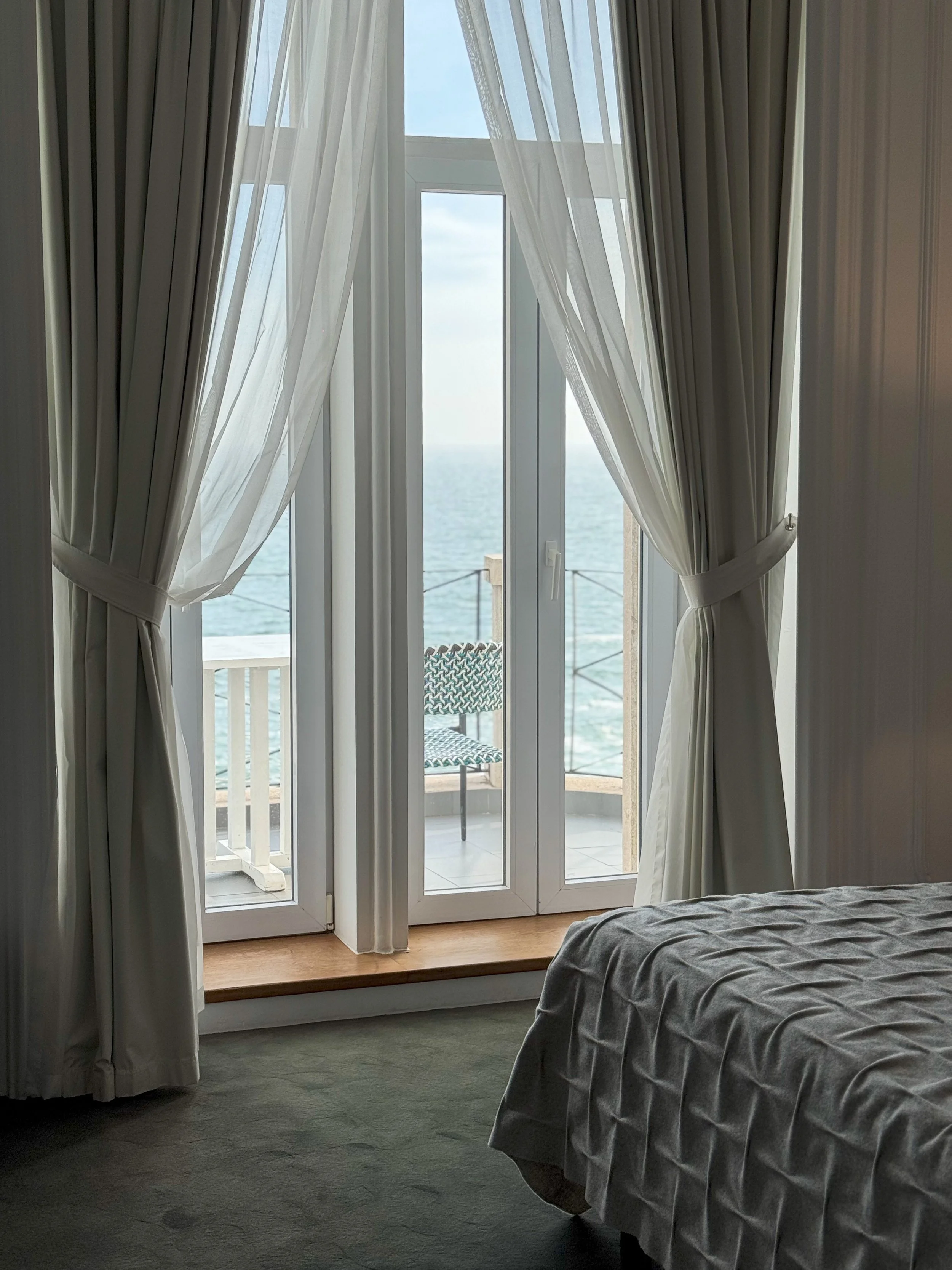 Light-filled guest room opening onto a private balcony with uninterrupted Atlantic Ocean views
