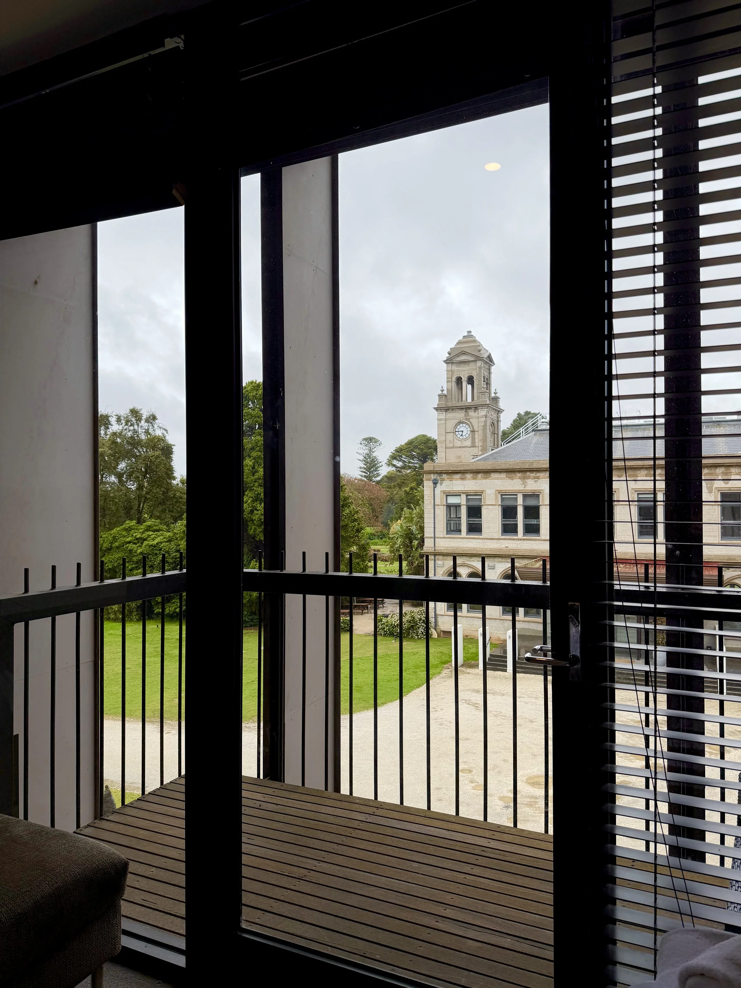 Private balcony overlooking the historic mansion's clock tower, landscaped gardens, and surrounding greenery
