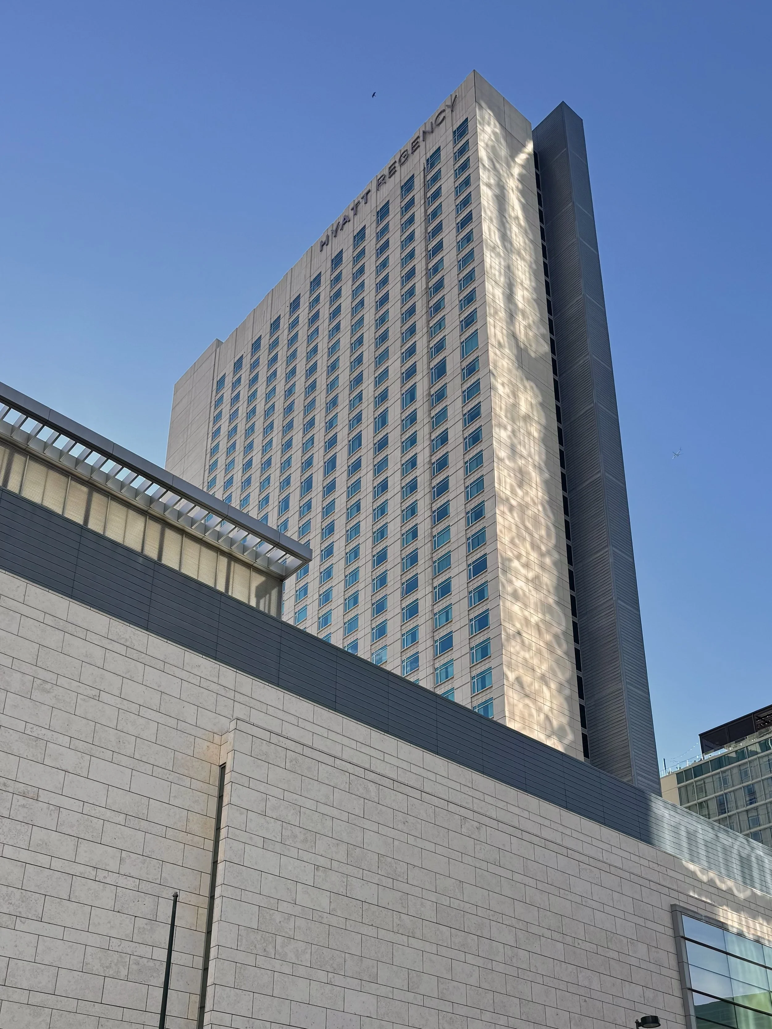 Exterior view of the Hyatt Regency Denver skyscraper rising above the Colorado Convention Center