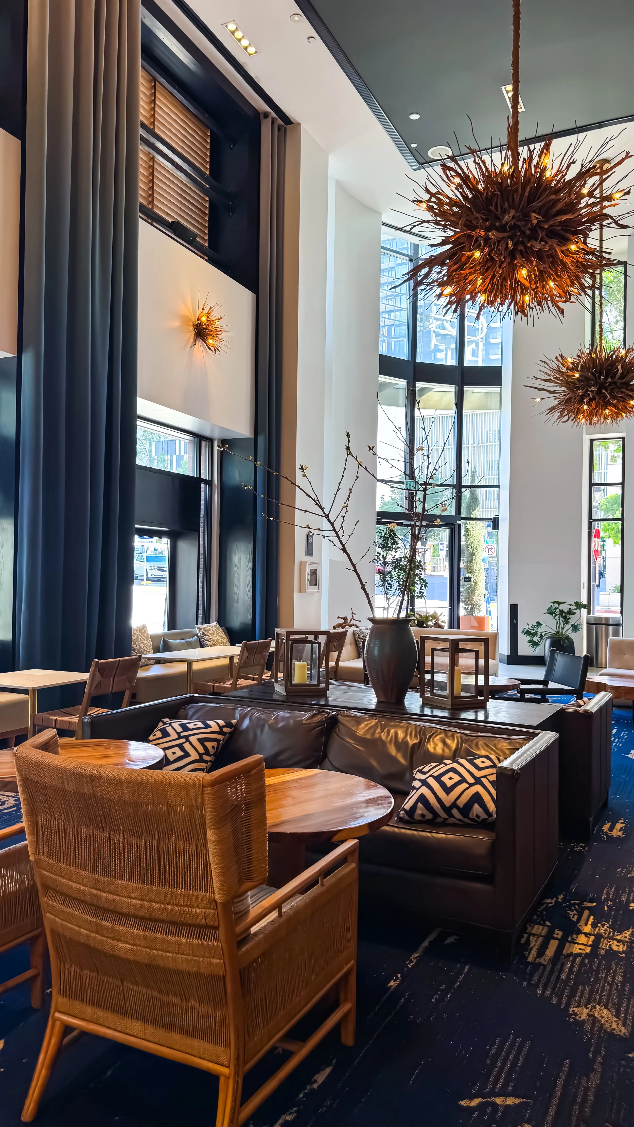 Lounge area with leather seating, wood tables, and warm ambient lighting beneath sculptural chandeliers, Hotel Republic San Diego – San Diego, California.
