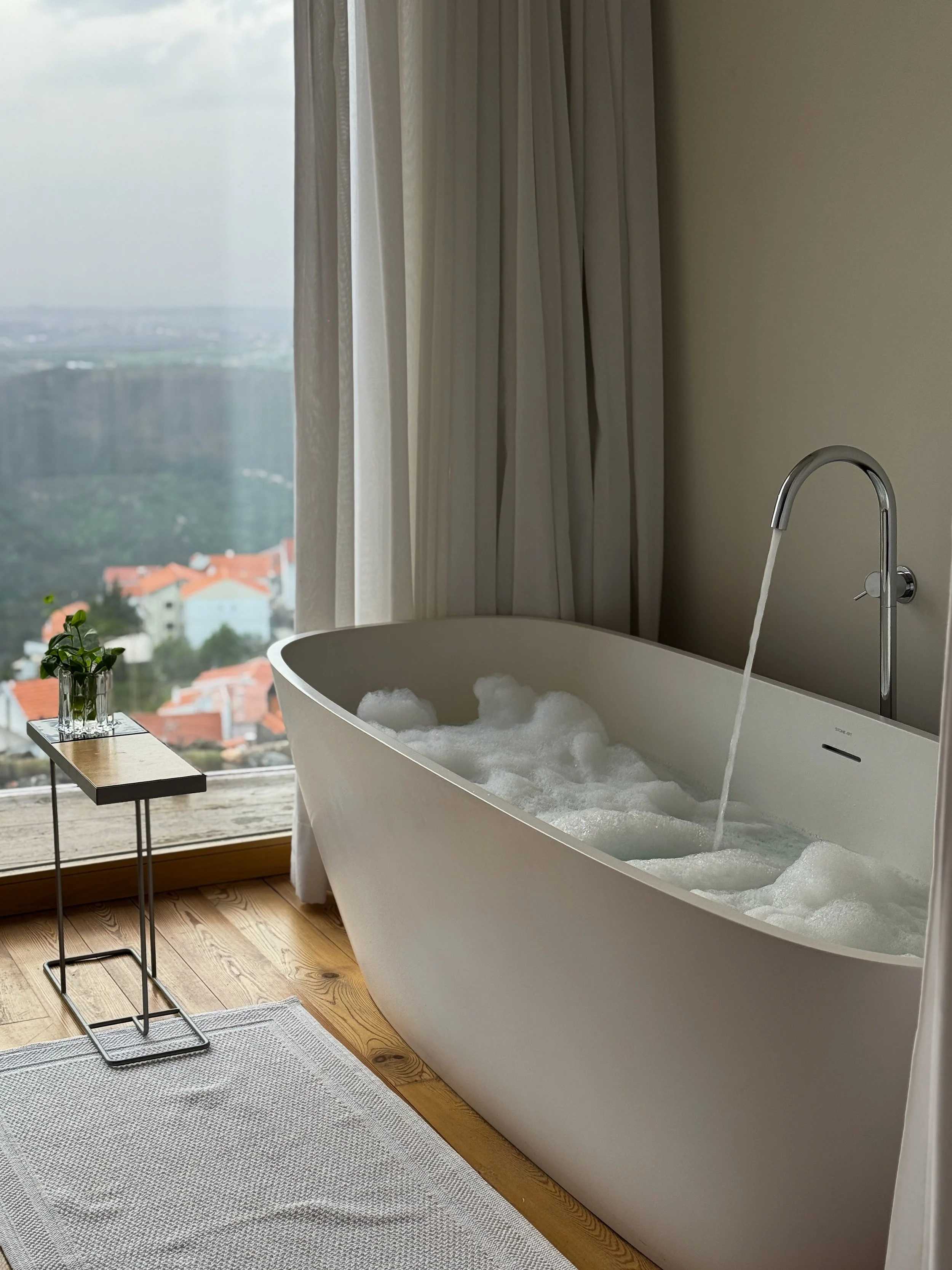 Freestanding bathtub with panoramic mountain views and natural light at Casas da Lapa in Serra da Estrela, Portugal