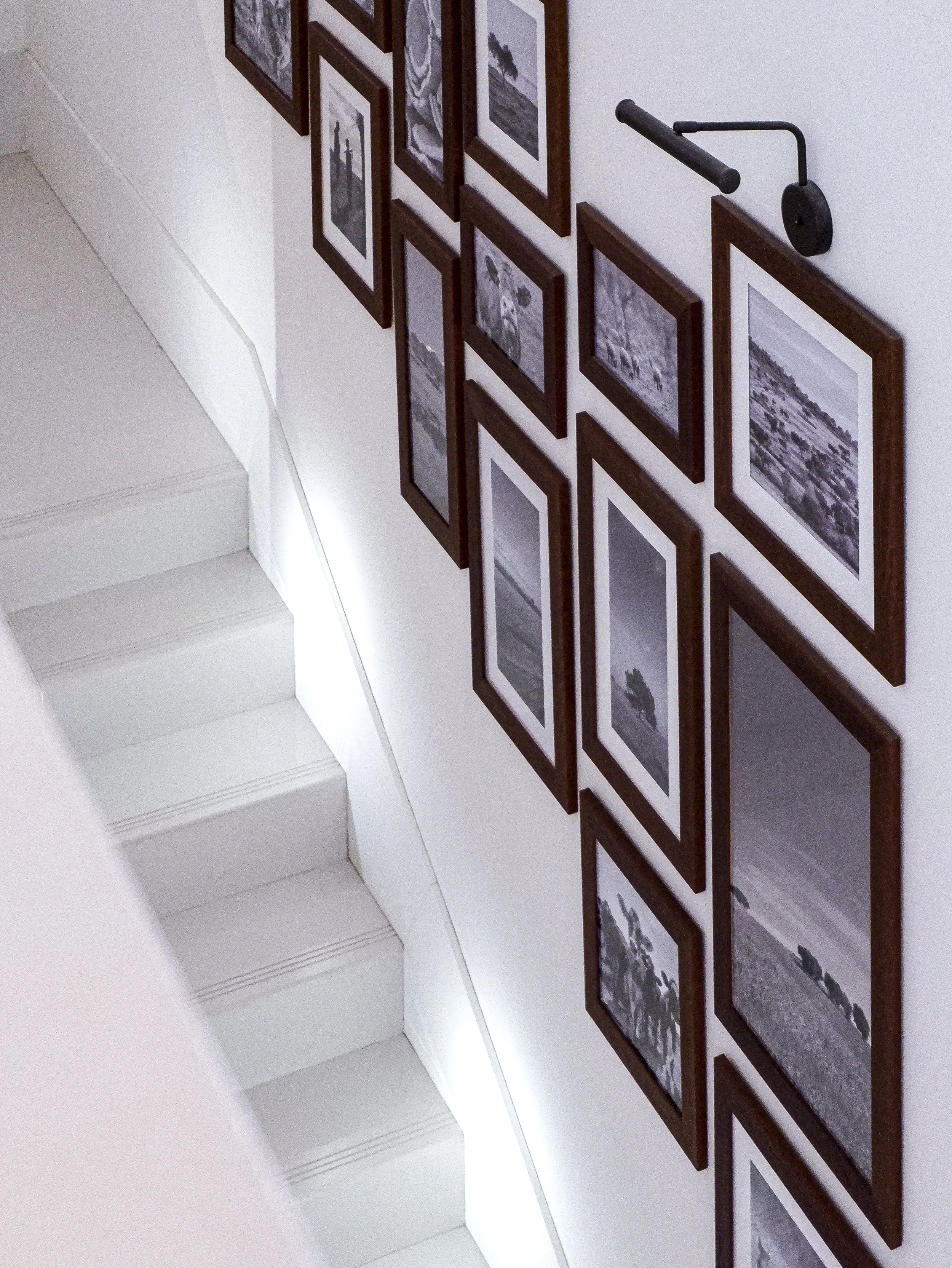 Clean white staircase lined with framed black-and-white photography inspired by the surrounding region — Octant Évora