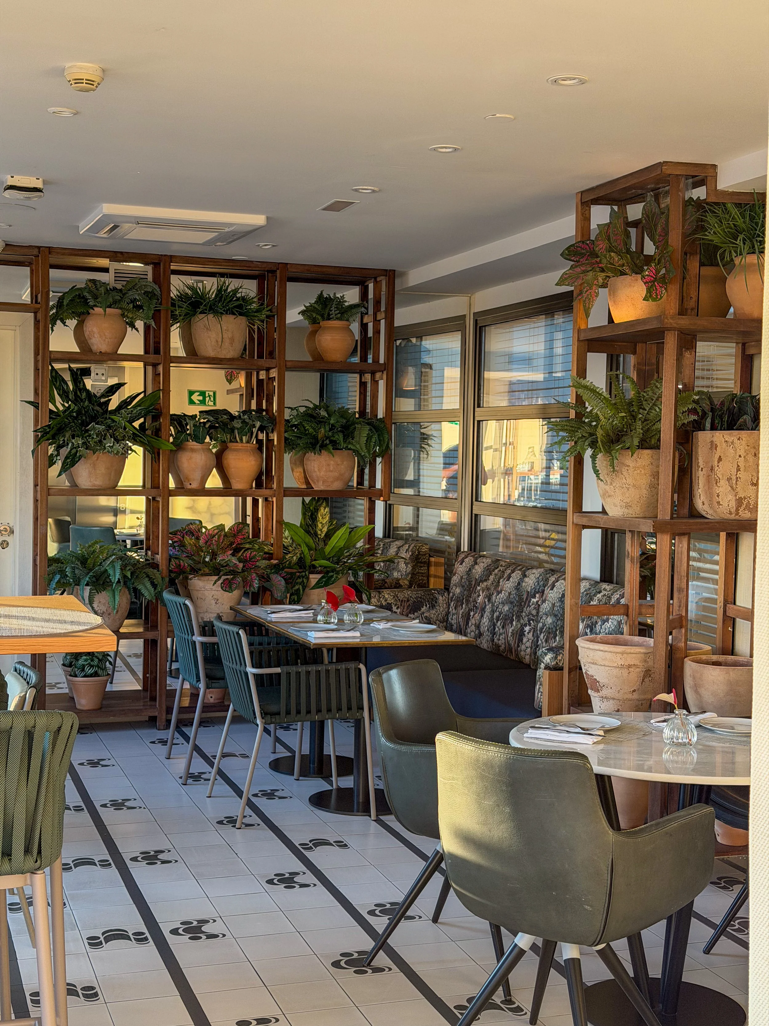 Modern restaurant combining Mediterranean design, lush greenery, and relaxed dining spaces