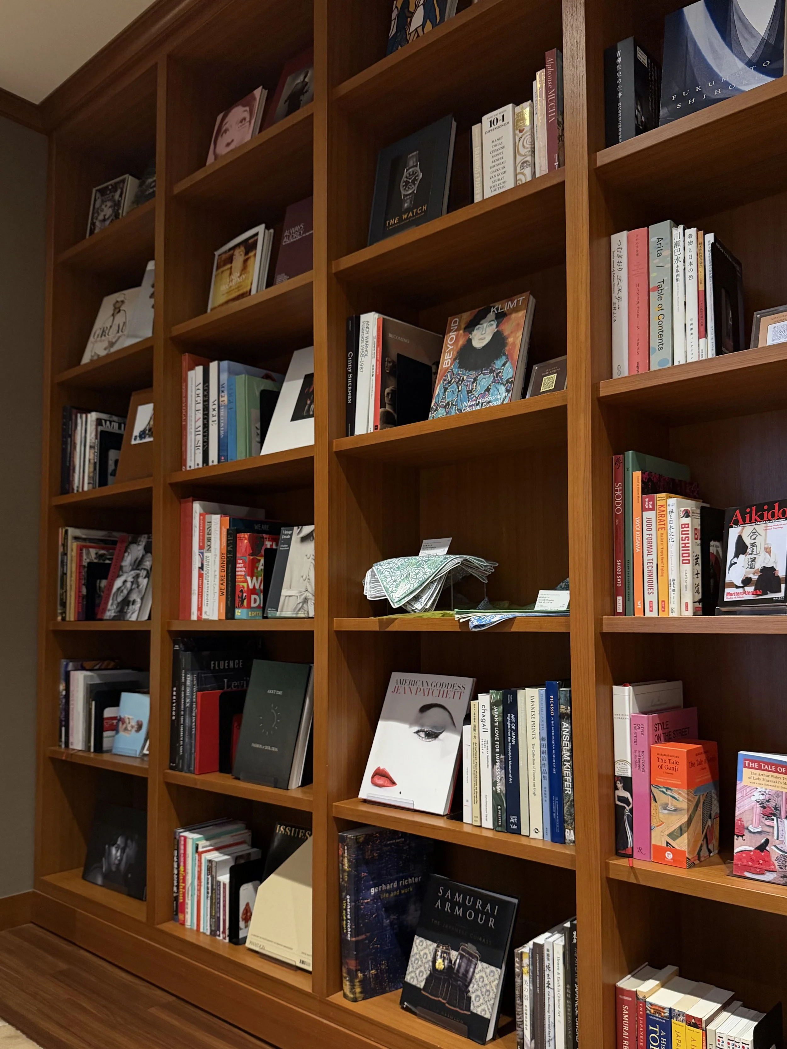 Floor-to-ceiling wooden bookshelves featuring a diverse collection of Japanese and international titles