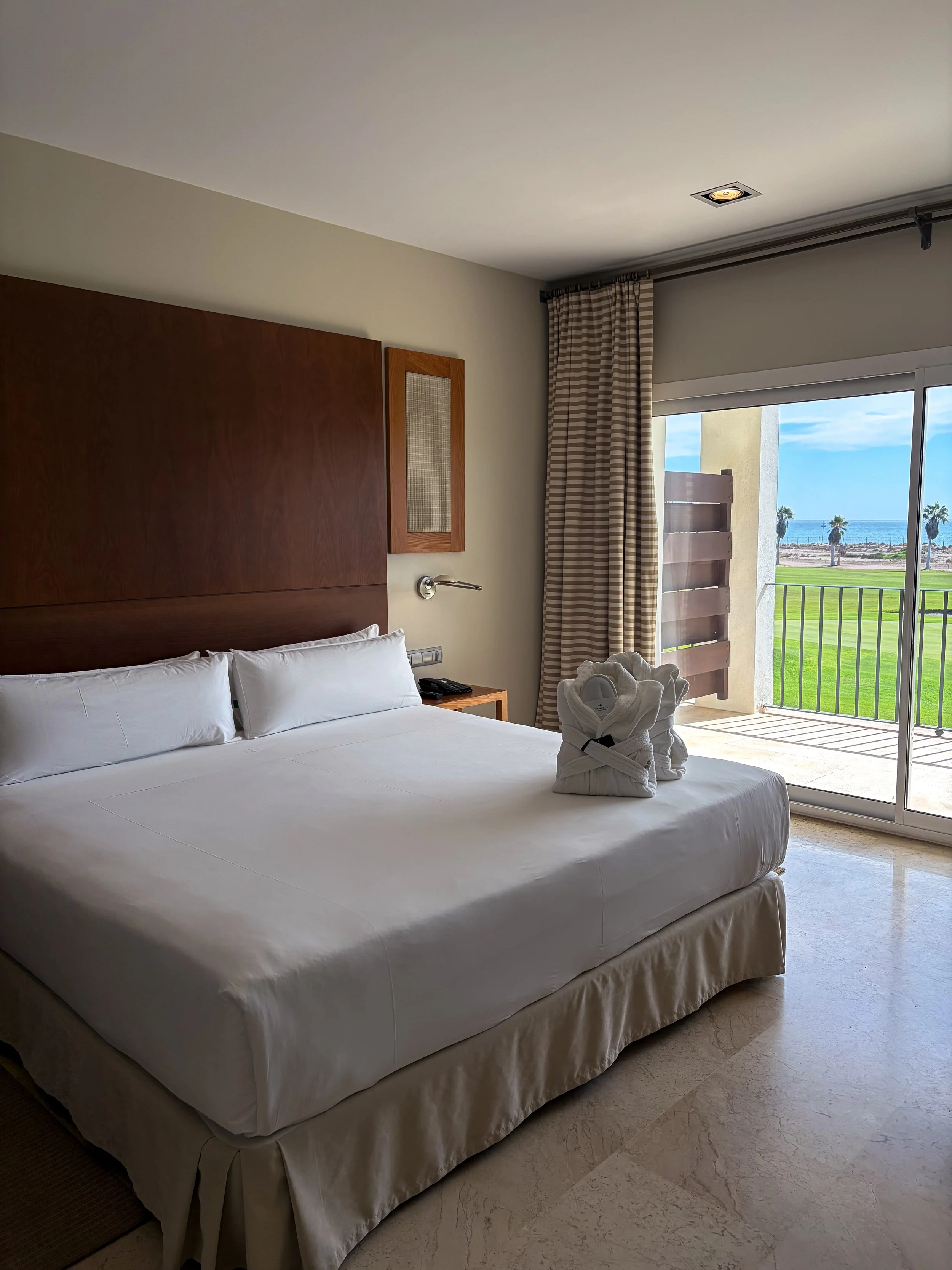 Bright guest room with private balcony overlooking the golf course and sea
