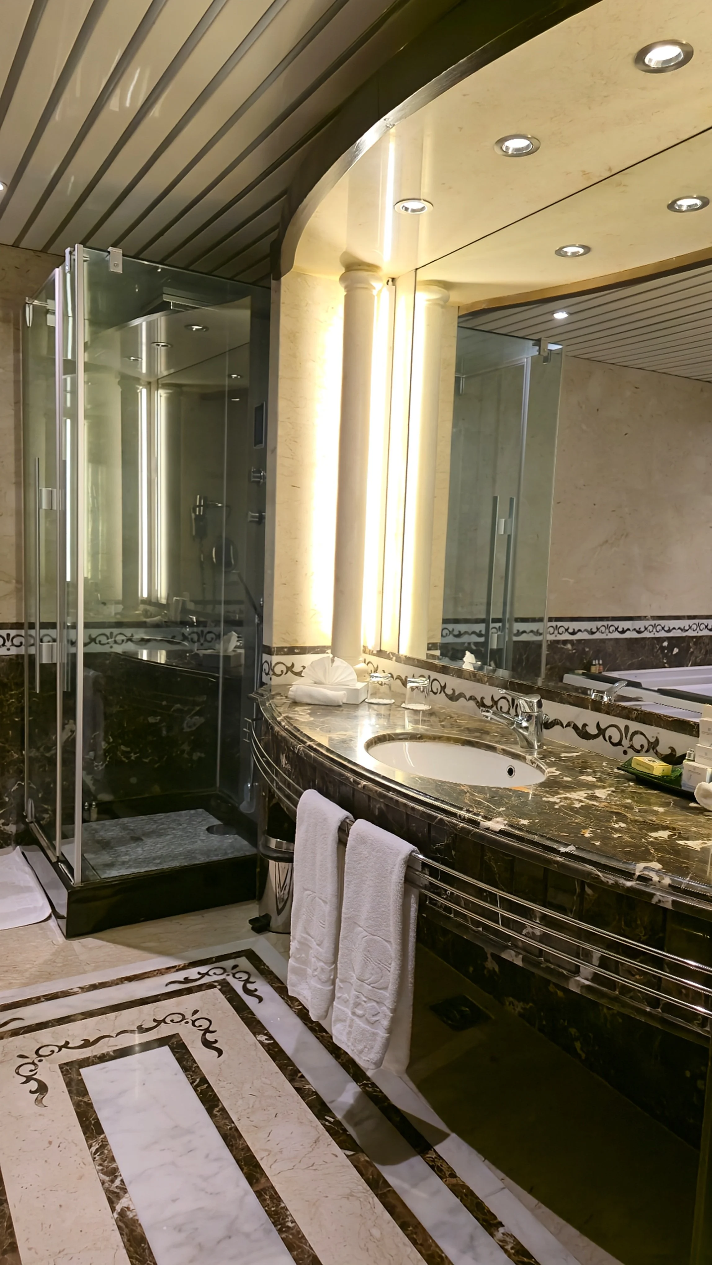Marble bathroom with curved vanity, glass shower, and polished stone finishes in a luxurious setting, Sonesta St. George Hotel Luxor.