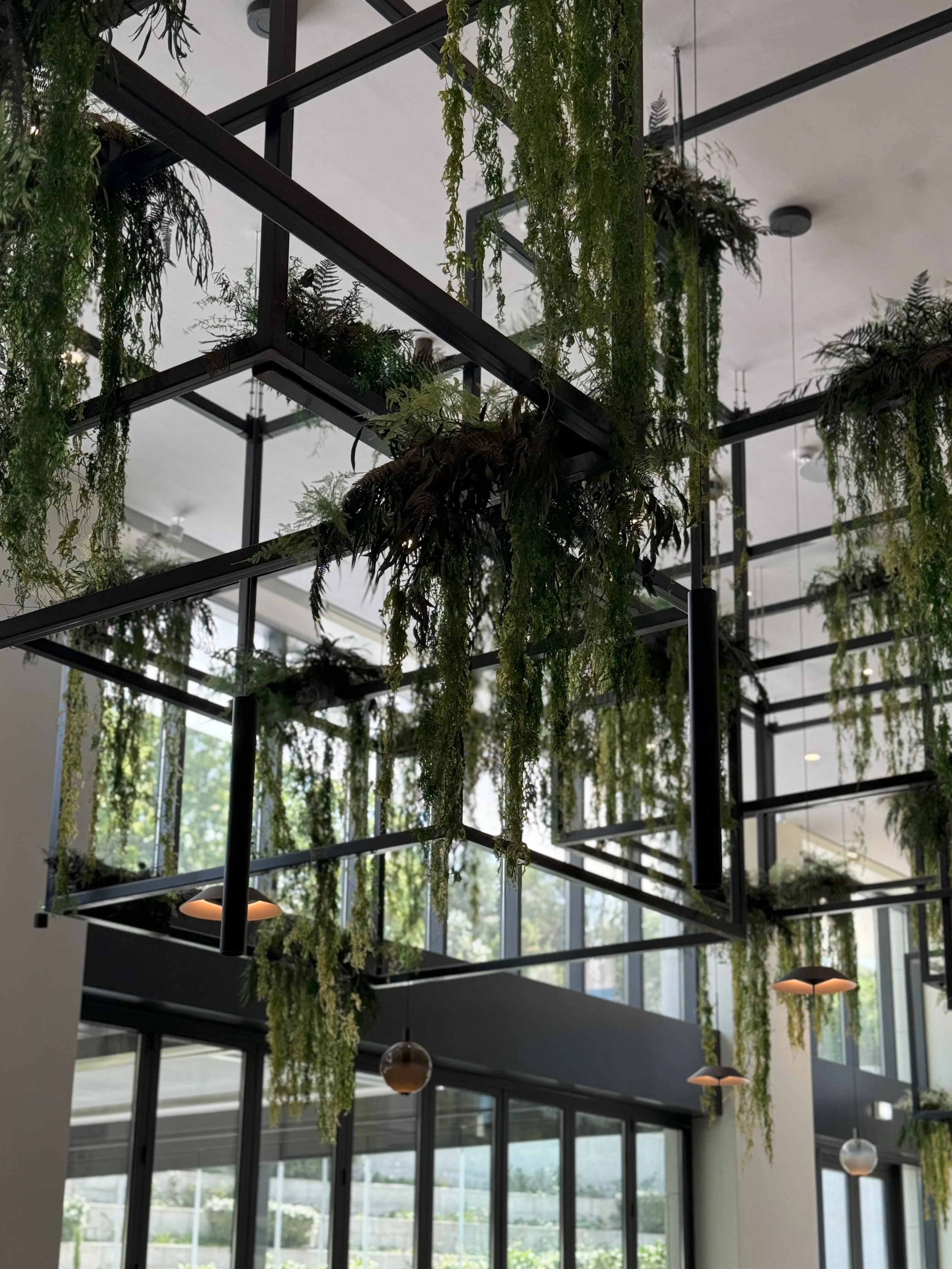 Double-height lobby featuring suspended greenery and abundant natural light