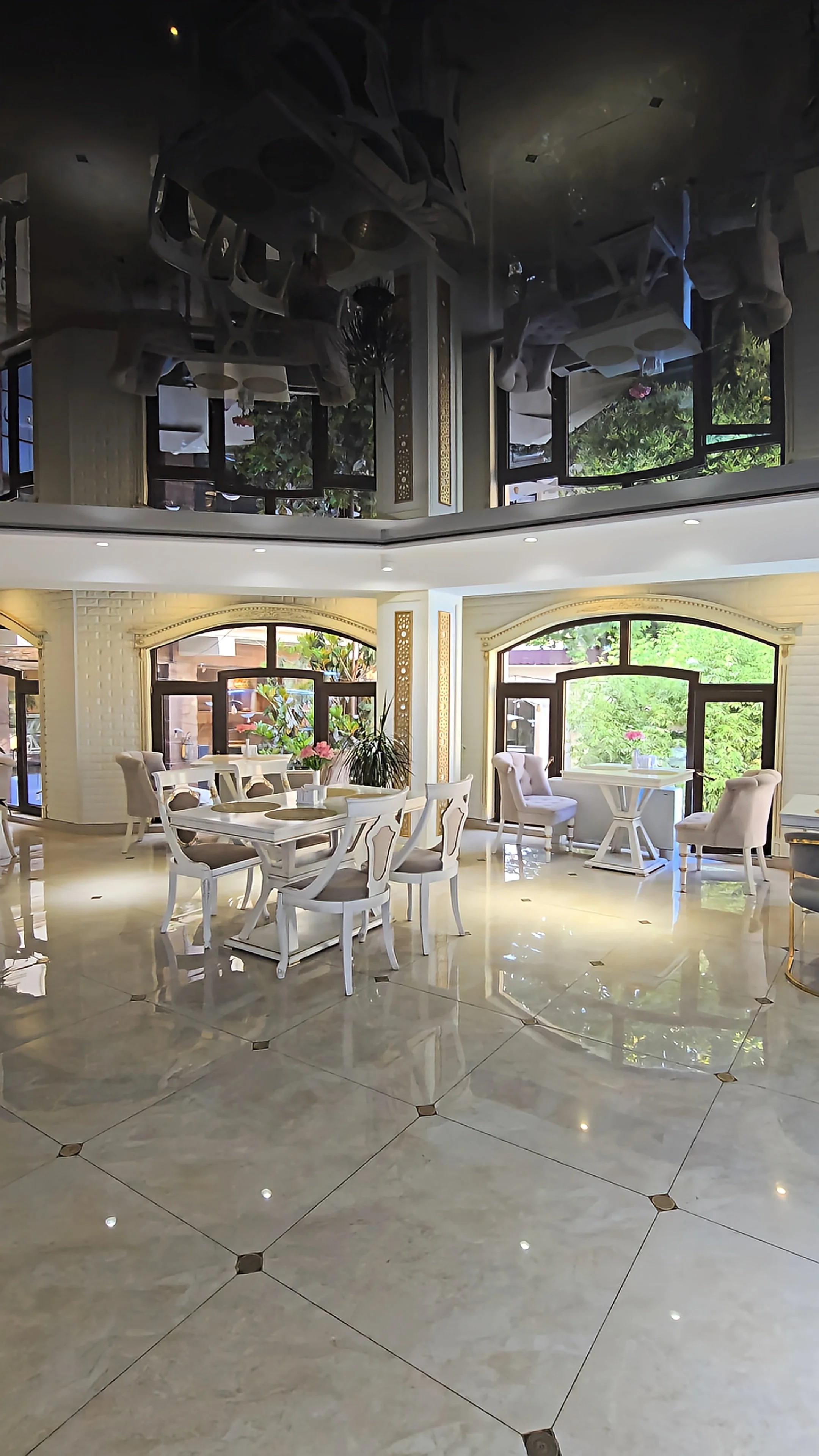 Bright indoor restaurant with marble floors, refined furnishings, and views of the landscaped courtyard