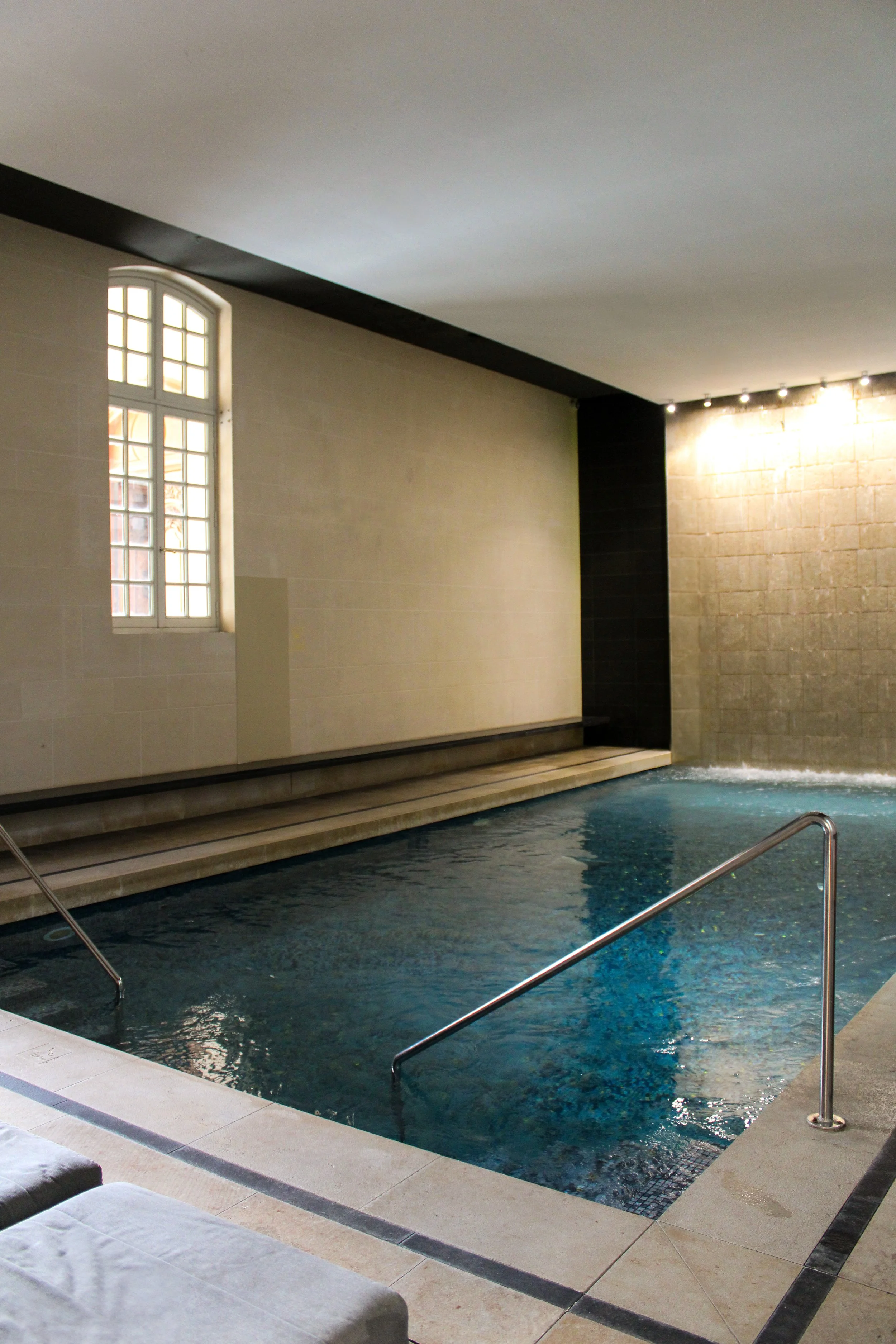 Indoor swimming pool with waterfall feature and tranquil spa atmosphere