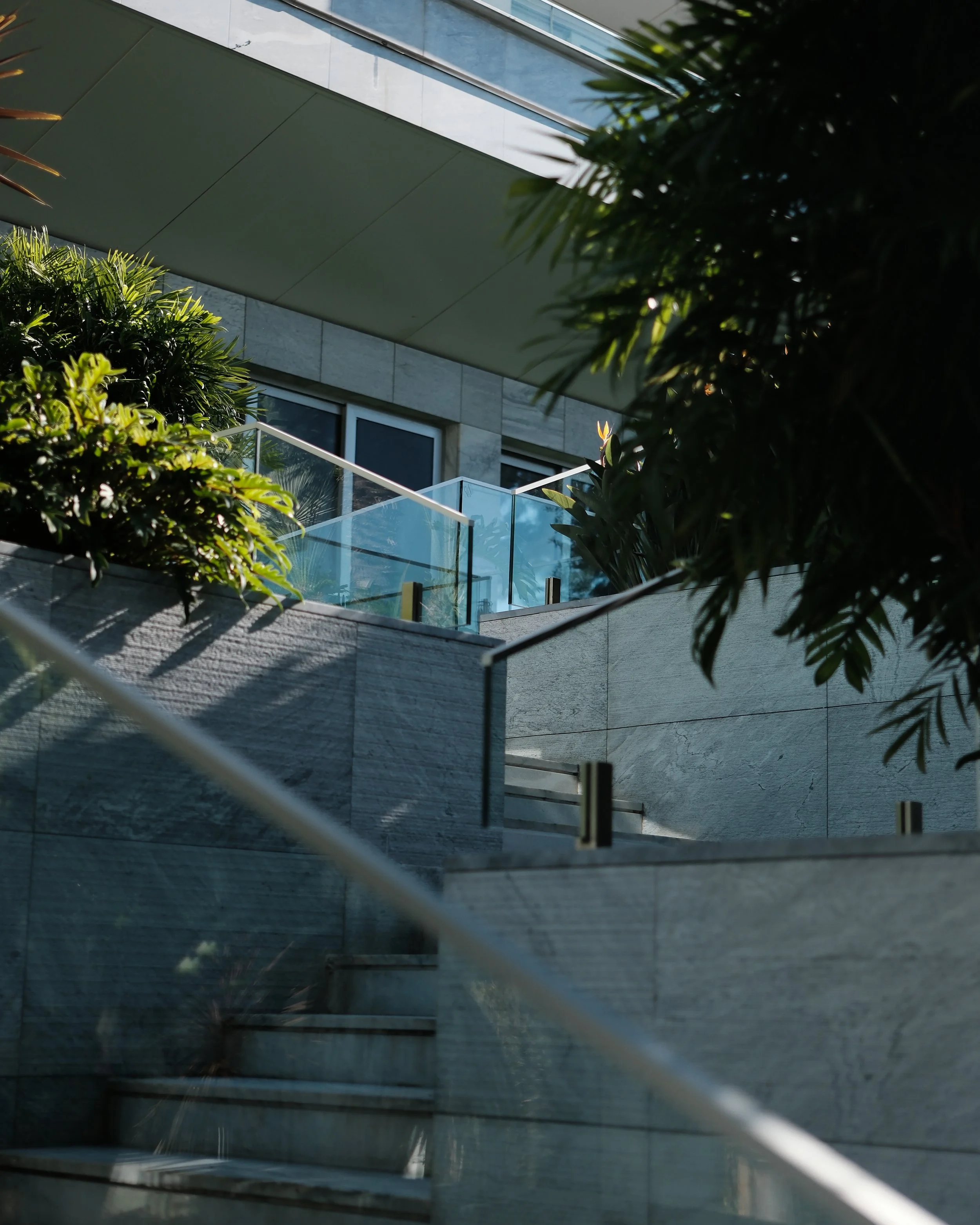Contemporary outdoor staircase with glass railings surrounded by lush greenery and modern stone finishes — Hyatt Regency Lisbon