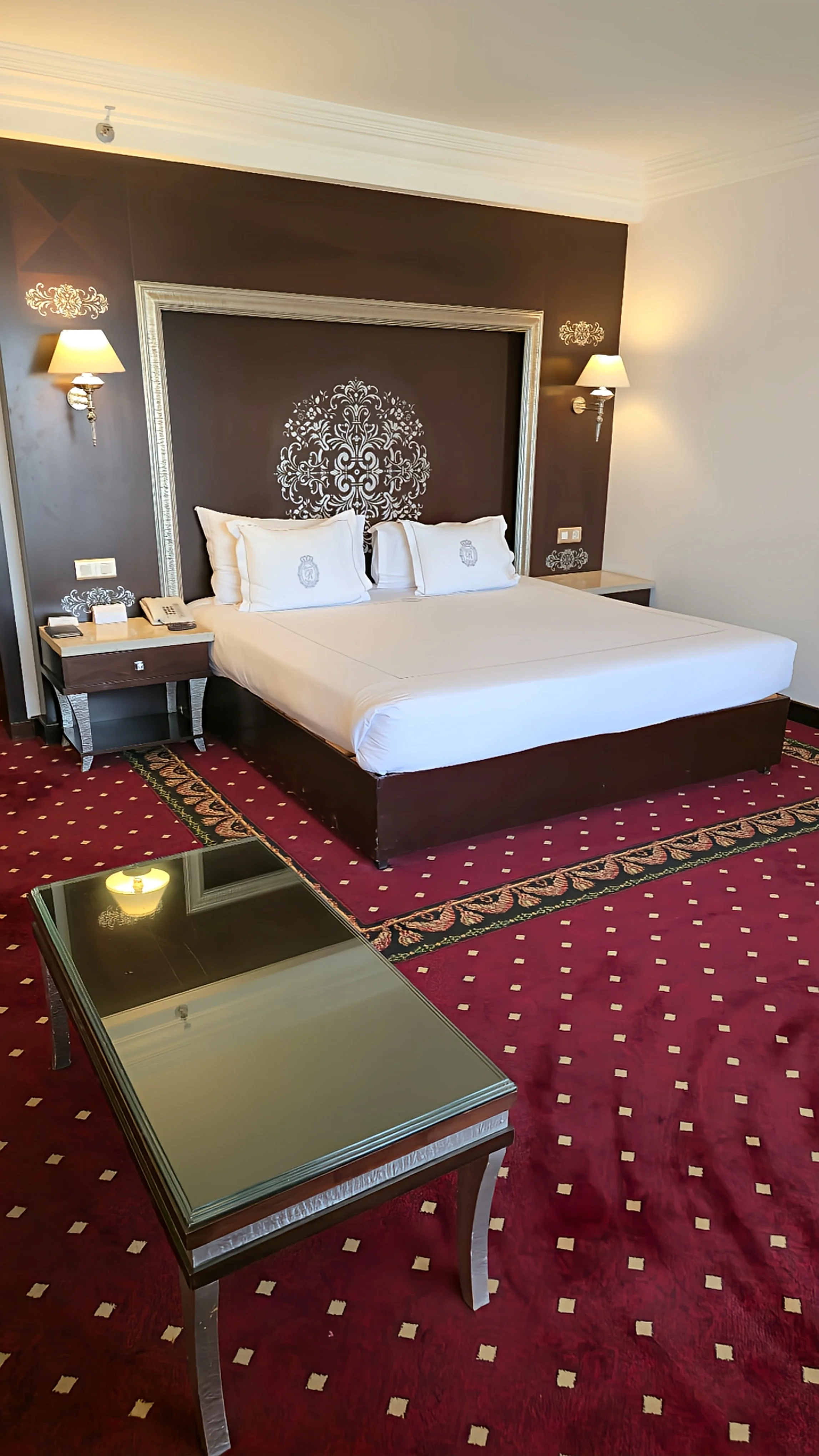 Classic king bedroom with ornate headboard, red carpet, and warm lighting creating an elegant, traditional atmosphere, Sonesta St. George Hotel Luxor.