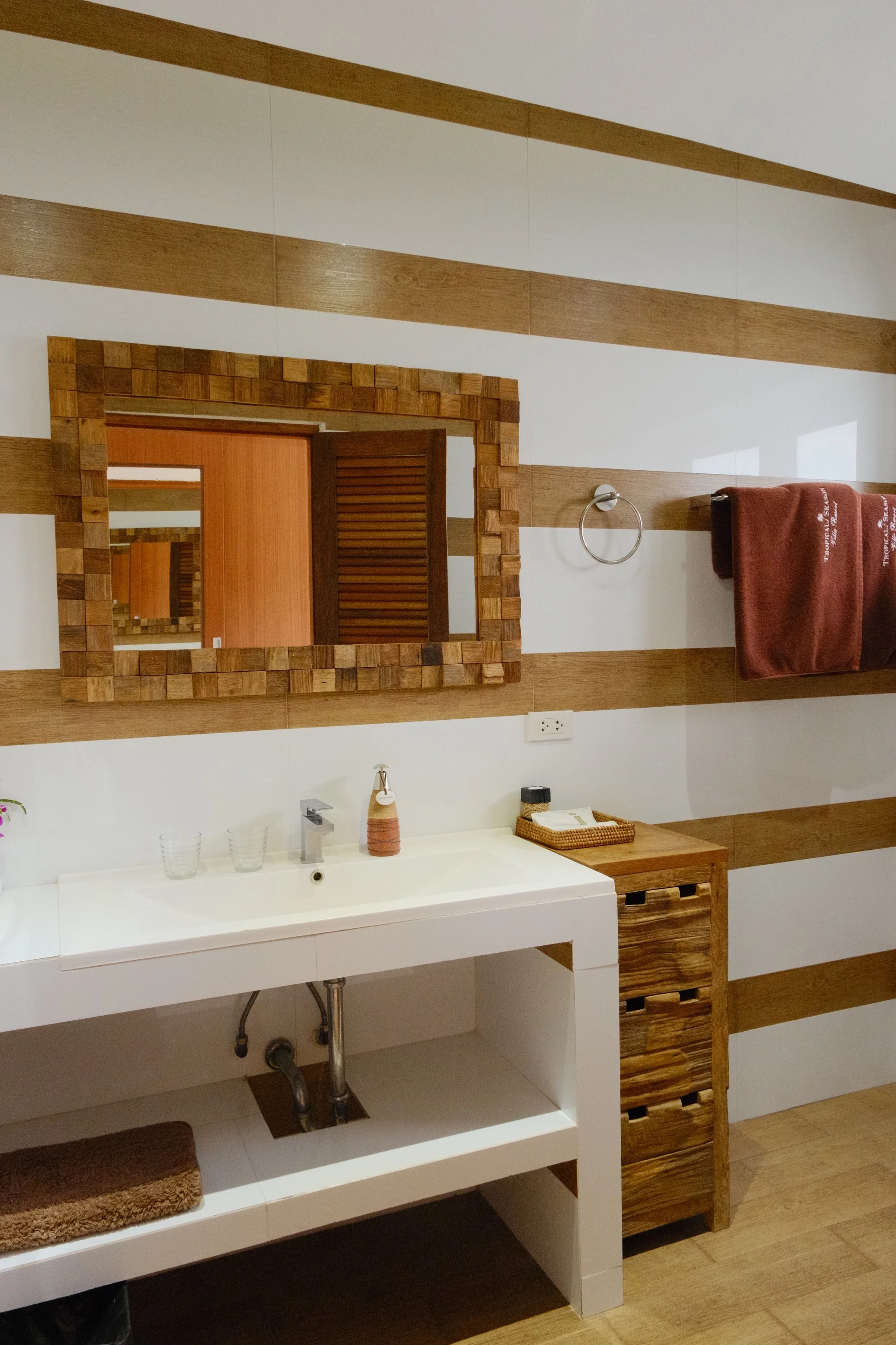 Contemporary villa bathroom with wood accents, geometric wall details, and a handcrafted mirror