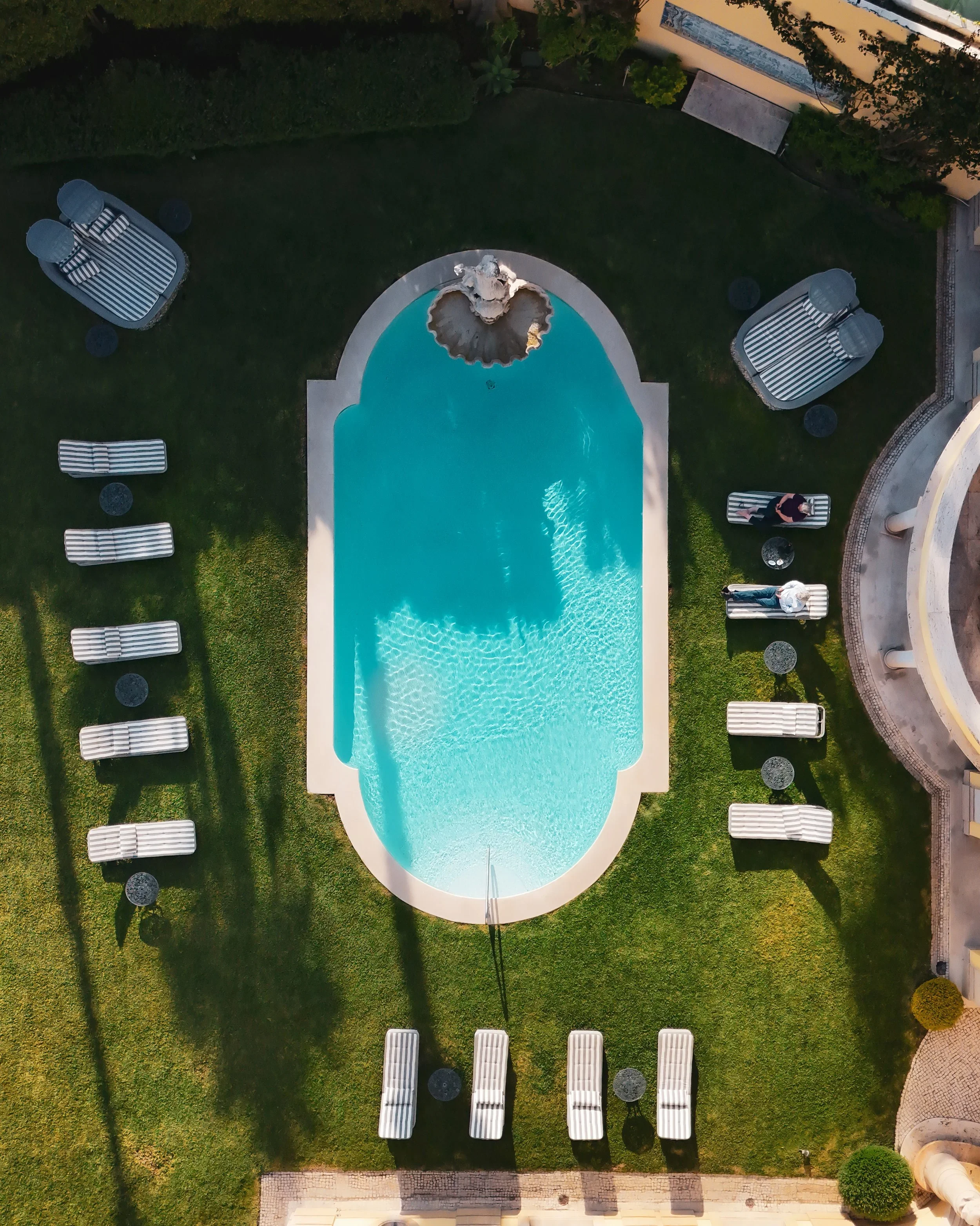 An aerial view reveals the elegant pool framed by manicured gardens and classical architecture