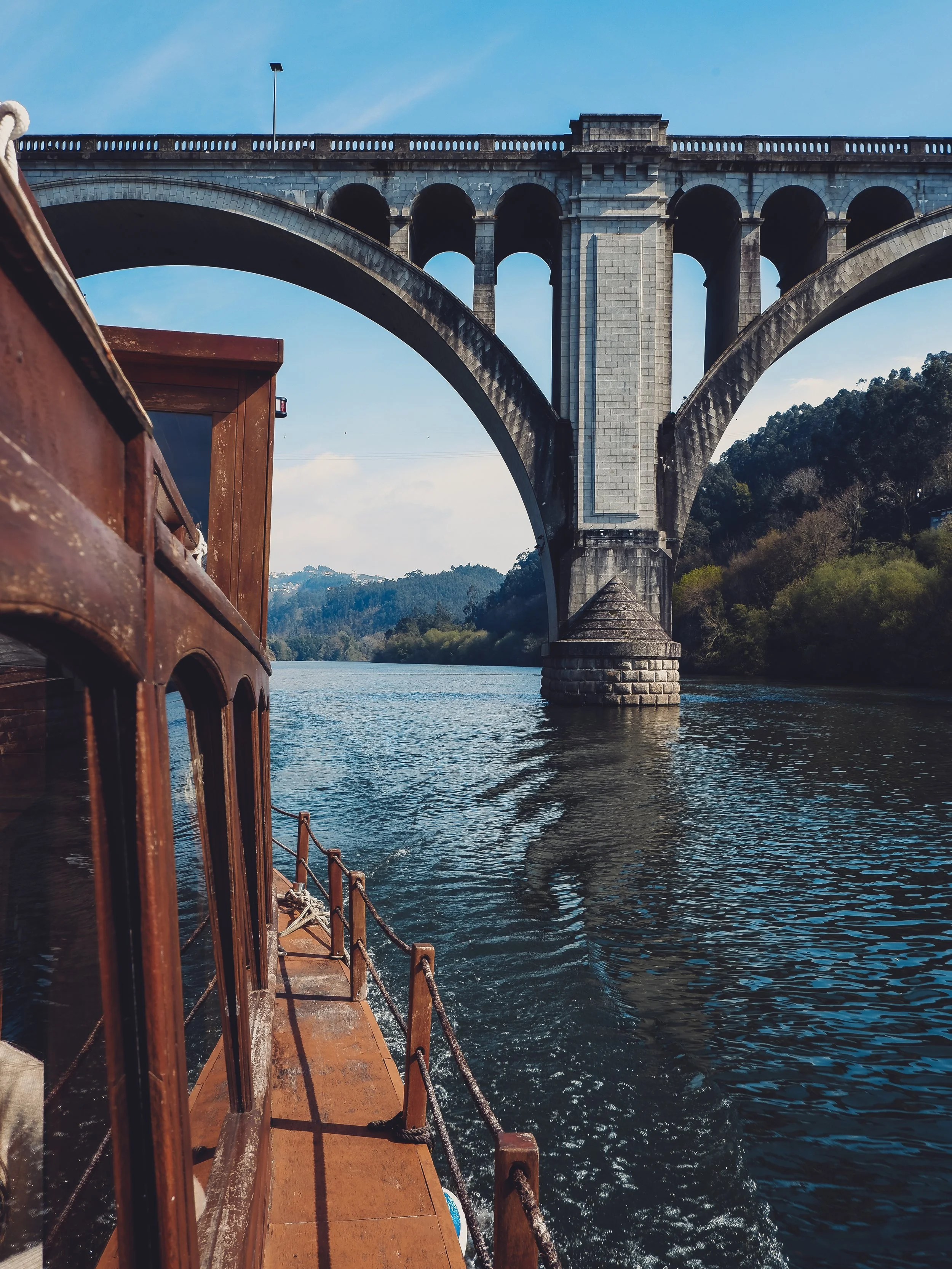Traditional wooden boat cruising beneath the iconic bridge during a scenic Douro River experience