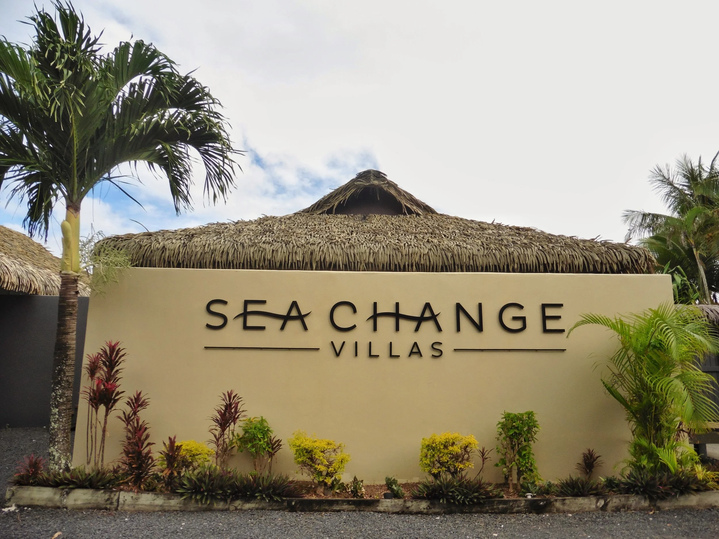Boutique resort entrance surrounded by tropical gardens and authentic Polynesian-inspired architecture