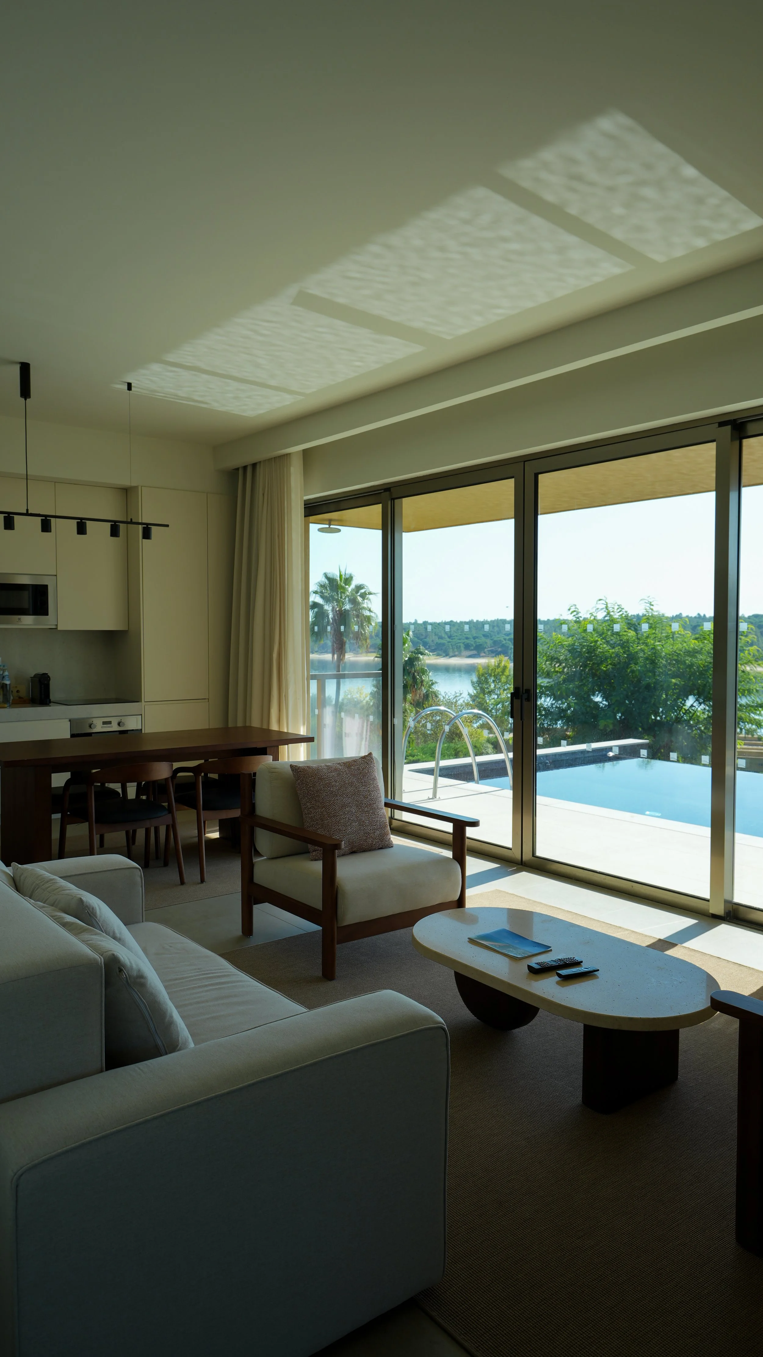 Contemporary villa living room with elegant furnishings, floor-to-ceiling windows, and a private pool overlooking the lake