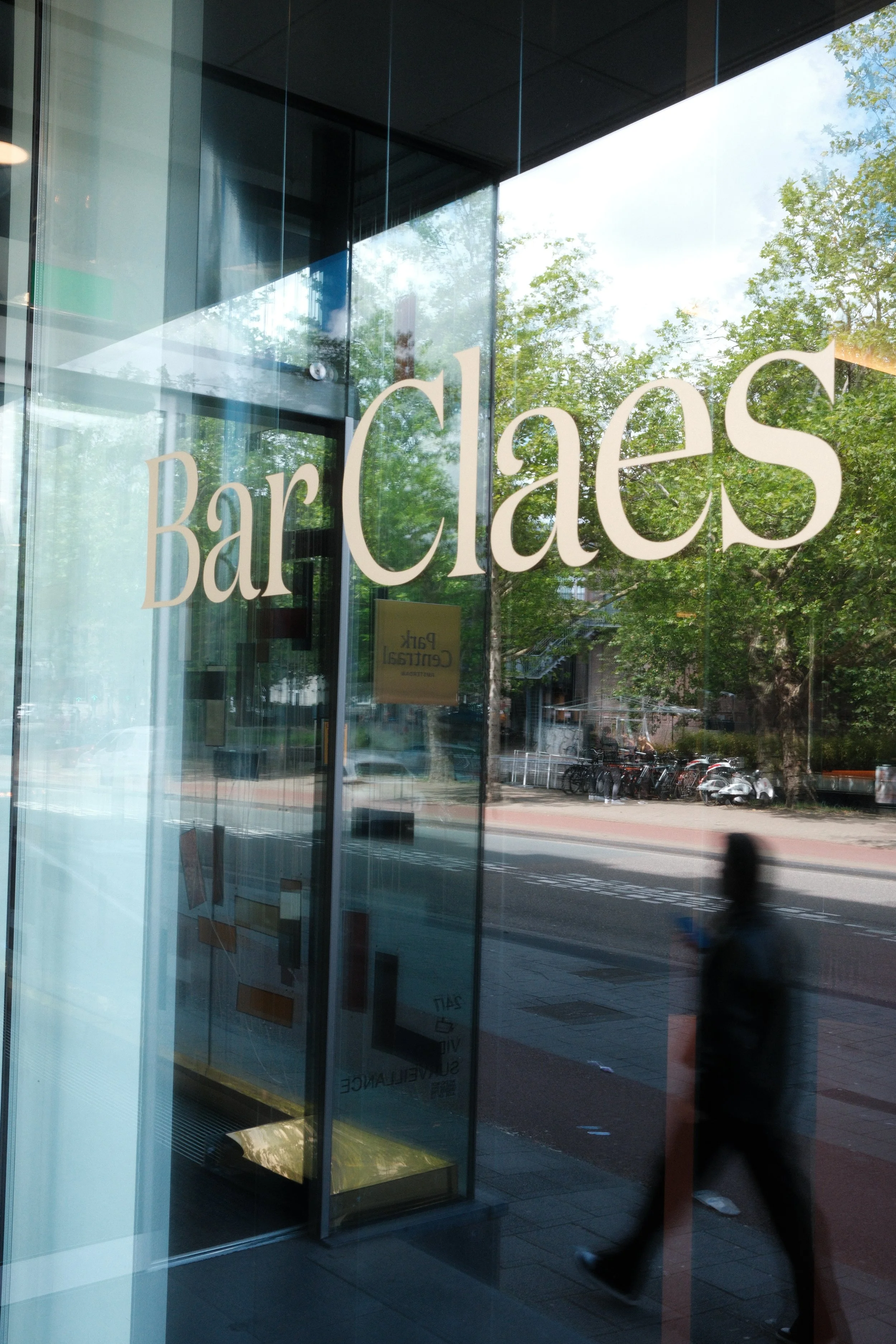 Bar Claes entrance overlooking Amsterdam’s lively streets through floor-to-ceiling glass