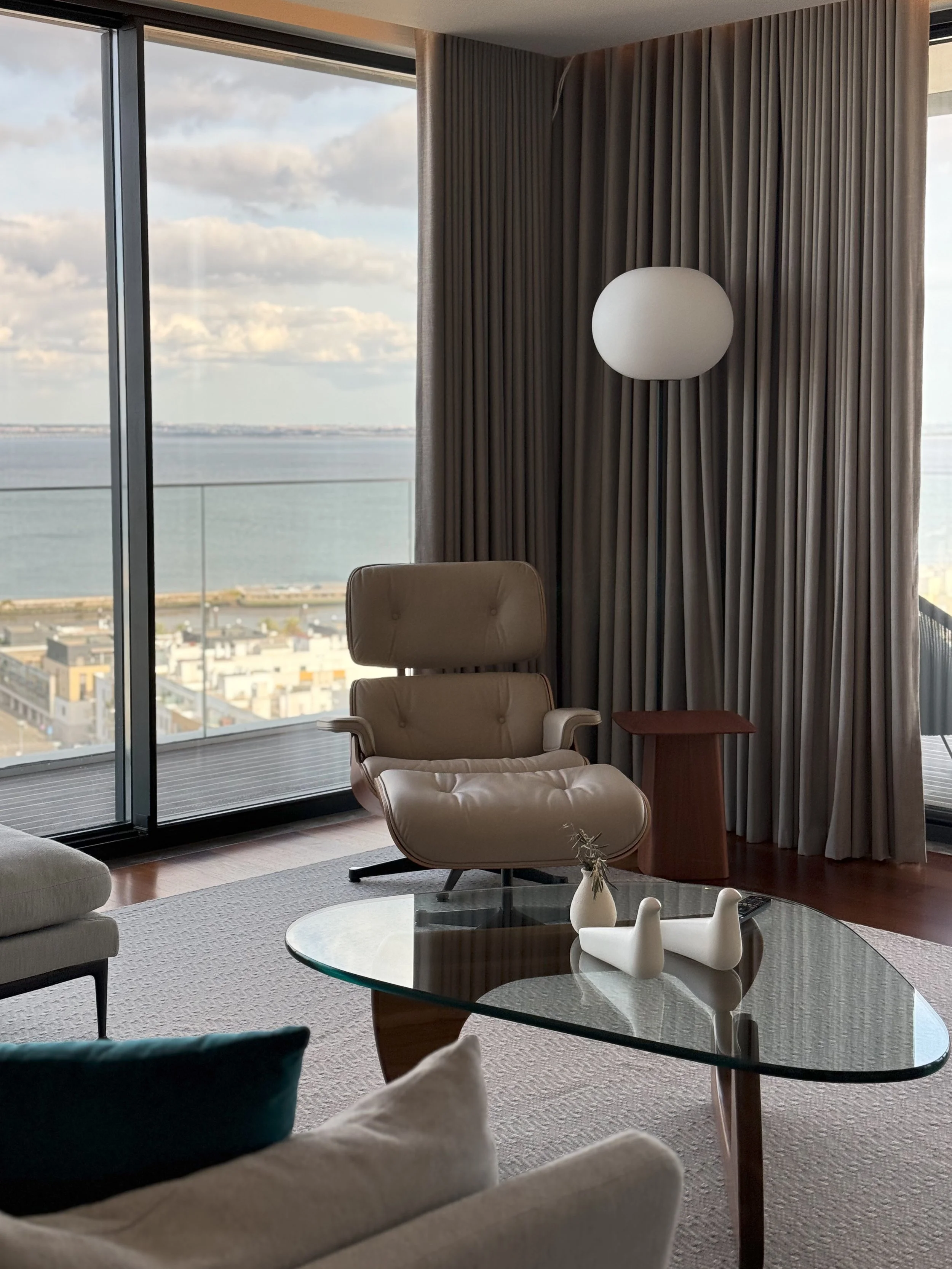 Elegant living area with panoramic river views, floor-to-ceiling windows, and mid-century design furniture, Martinhal Lisbon Oriente – Lisbon, Portugal.
